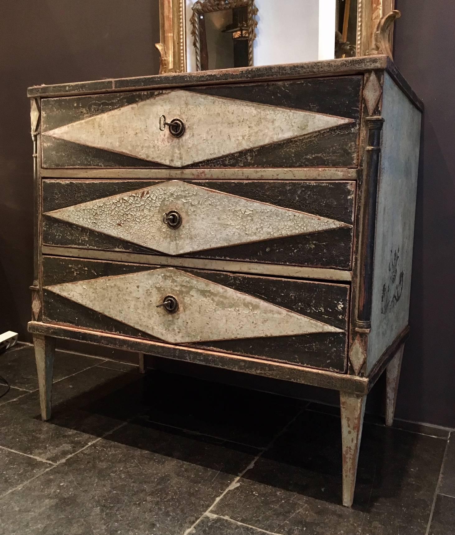 Charming antique commode with a beautiful patine and craquelure. The cabinet has three drawers, complete with locks and keys. 
The commode was painted in a light mint green and dark gray color. The paint shows beautiful deep crackles, which creates
