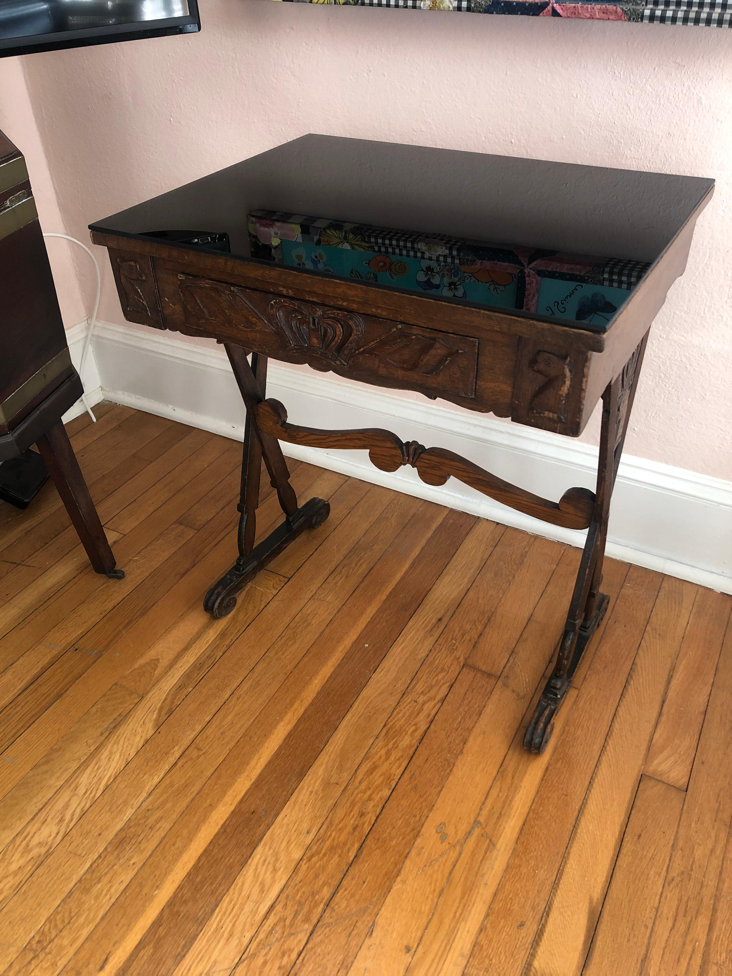 A masculine wonderfully weathered carved oak end table having single drawer with crown decoration and two animal motife heads that look like chess pieces on either side, as well as handsome X motife legs also decorated with crowns. Top has a