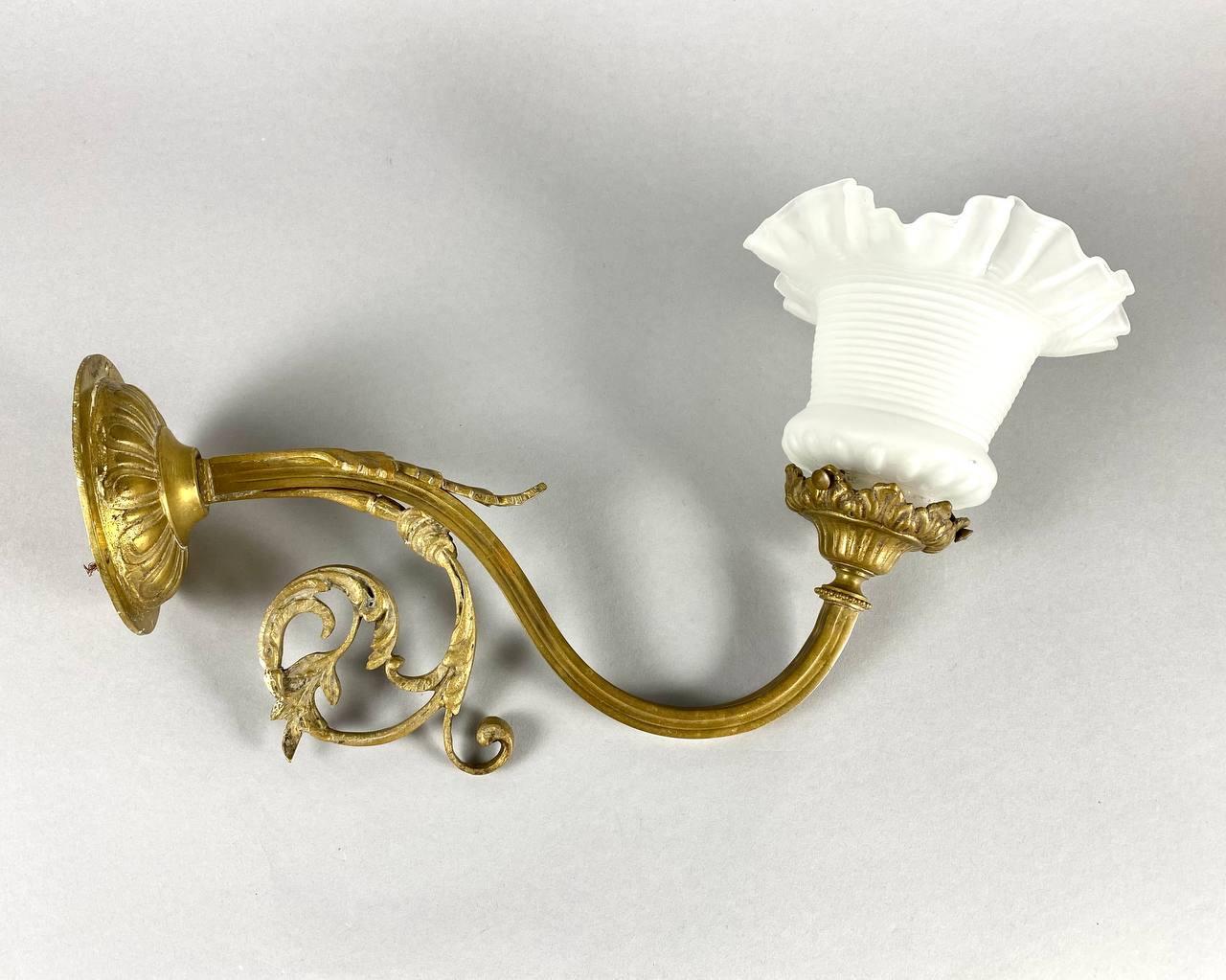 Ornate bronze wall sconce with gilt bronze arm with acanthus leaf detail and frosted frilled glass shade. 

 France, 1920s.

 Antique Baroque Style wall sconce.

 This is a highly decorative piece with beautiful glass shade. Individually
