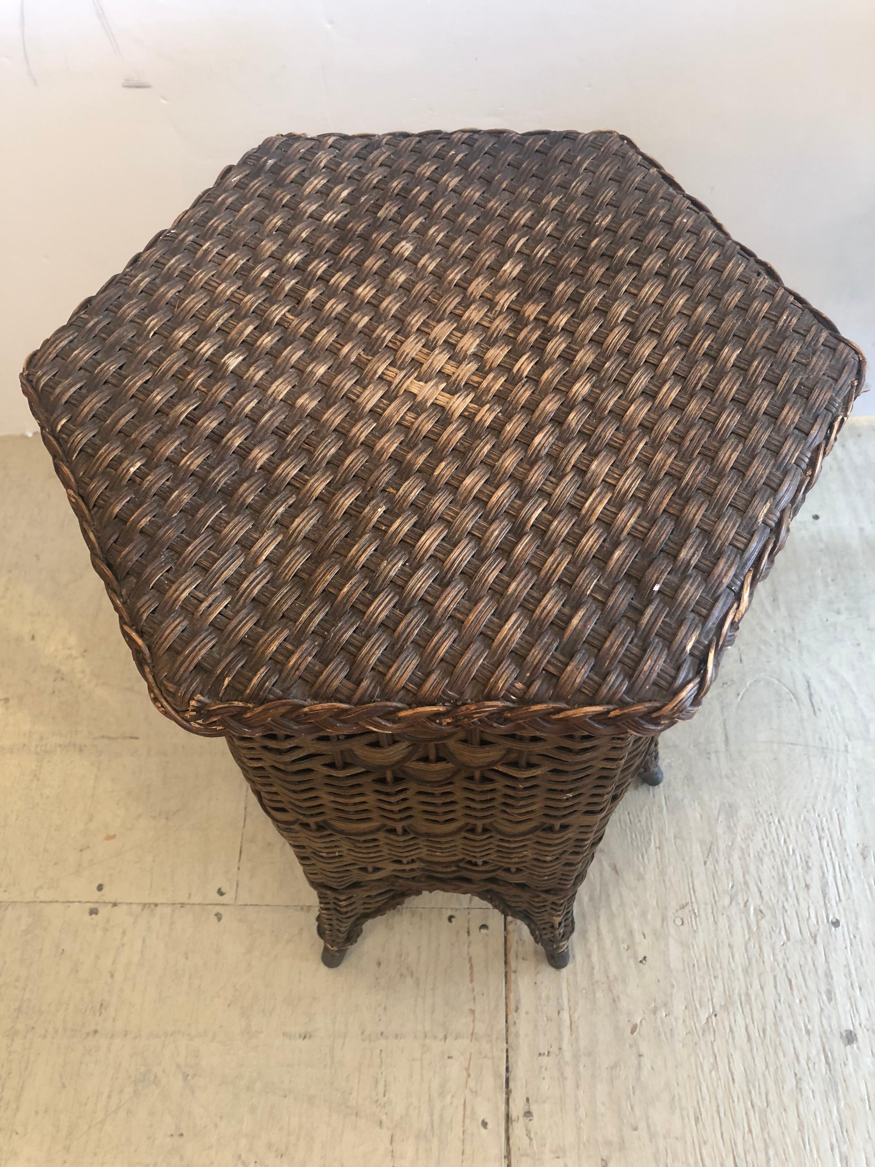 They don't make 'em like this anymore is a great way to describe this charming circa 1900 natural wicker and rattan hexagonal shaped drinks or end  side table having single door with storage inside. The adorable splayed feet are metal capped.
