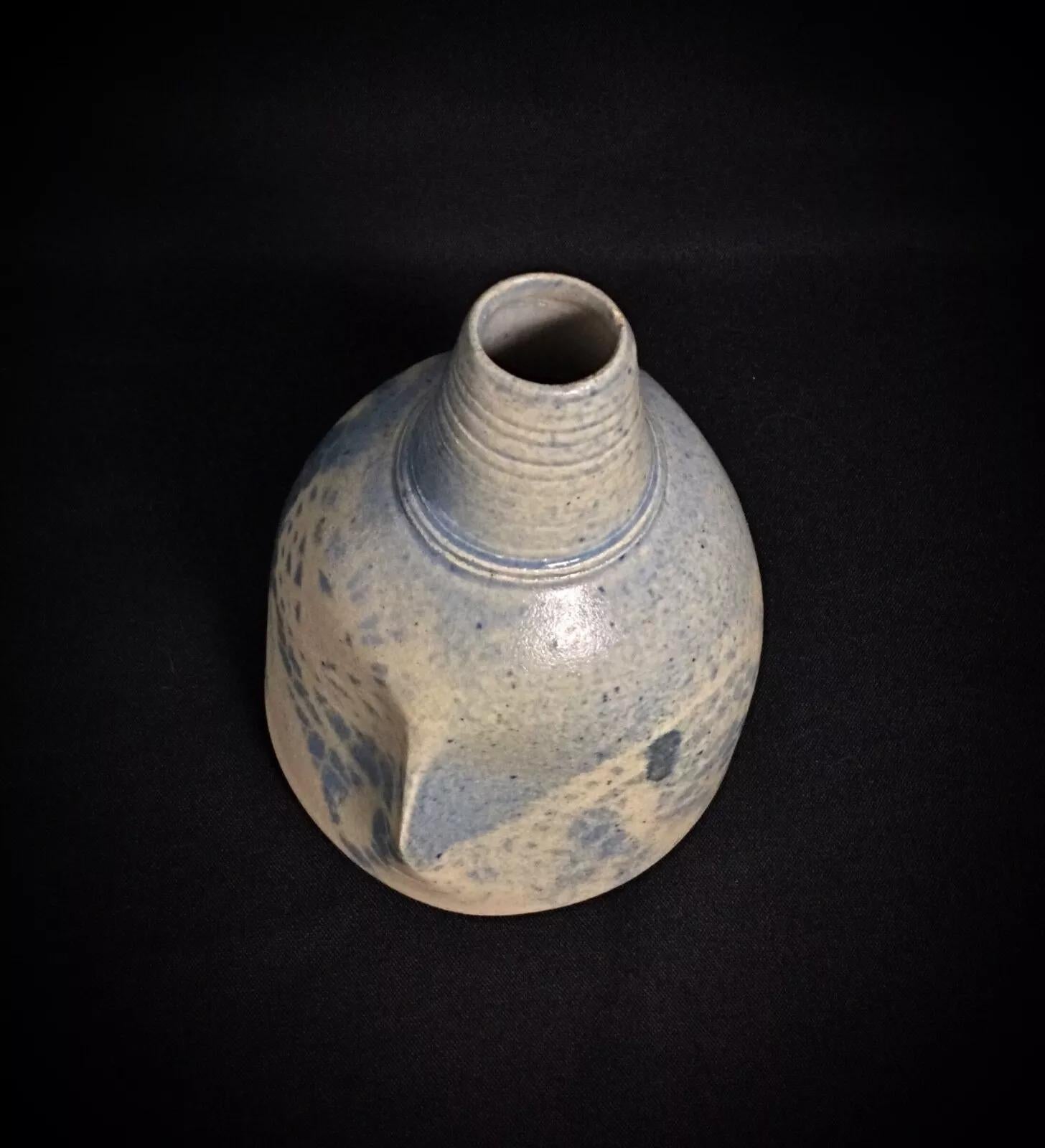 Este elegante jarrón soliflor de loza azul y blanca es un bello ejemplo del diseño del siglo XX. Firmada y numerada, muestra un estilo floral atemporal que añade un toque de sofisticación a cualquier espacio. Ideal para una sola flor o como acento