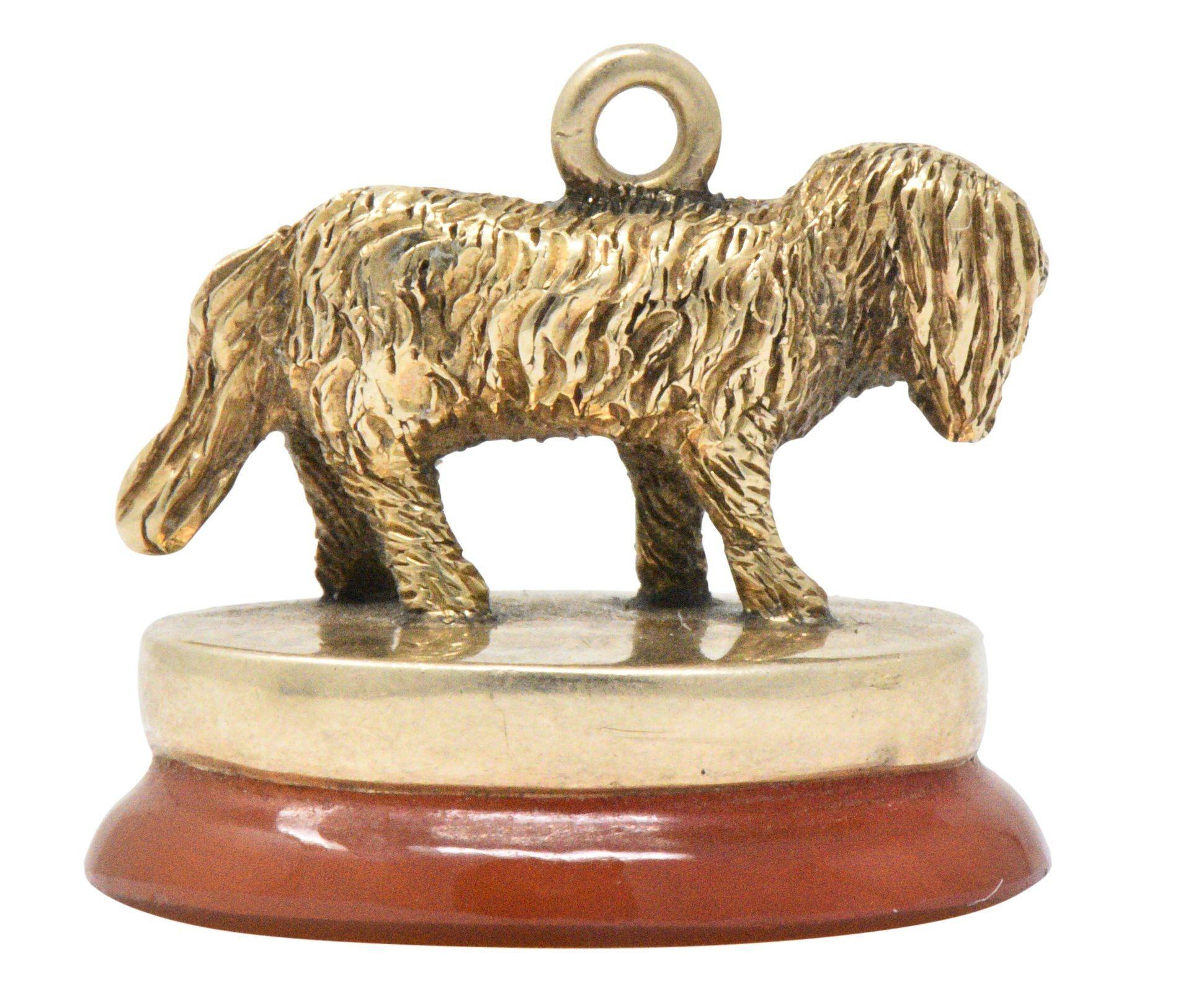 Fob style charm featuring a highly rendered shaggy dog figure with extremely textured fur

Perched upon an oval carnelian base, polished, and a deep orangey-red color

Tested as 14 karat gold

Circa: 1880s

Length: 3/4 inch

Height: 1/2 inch

Total
