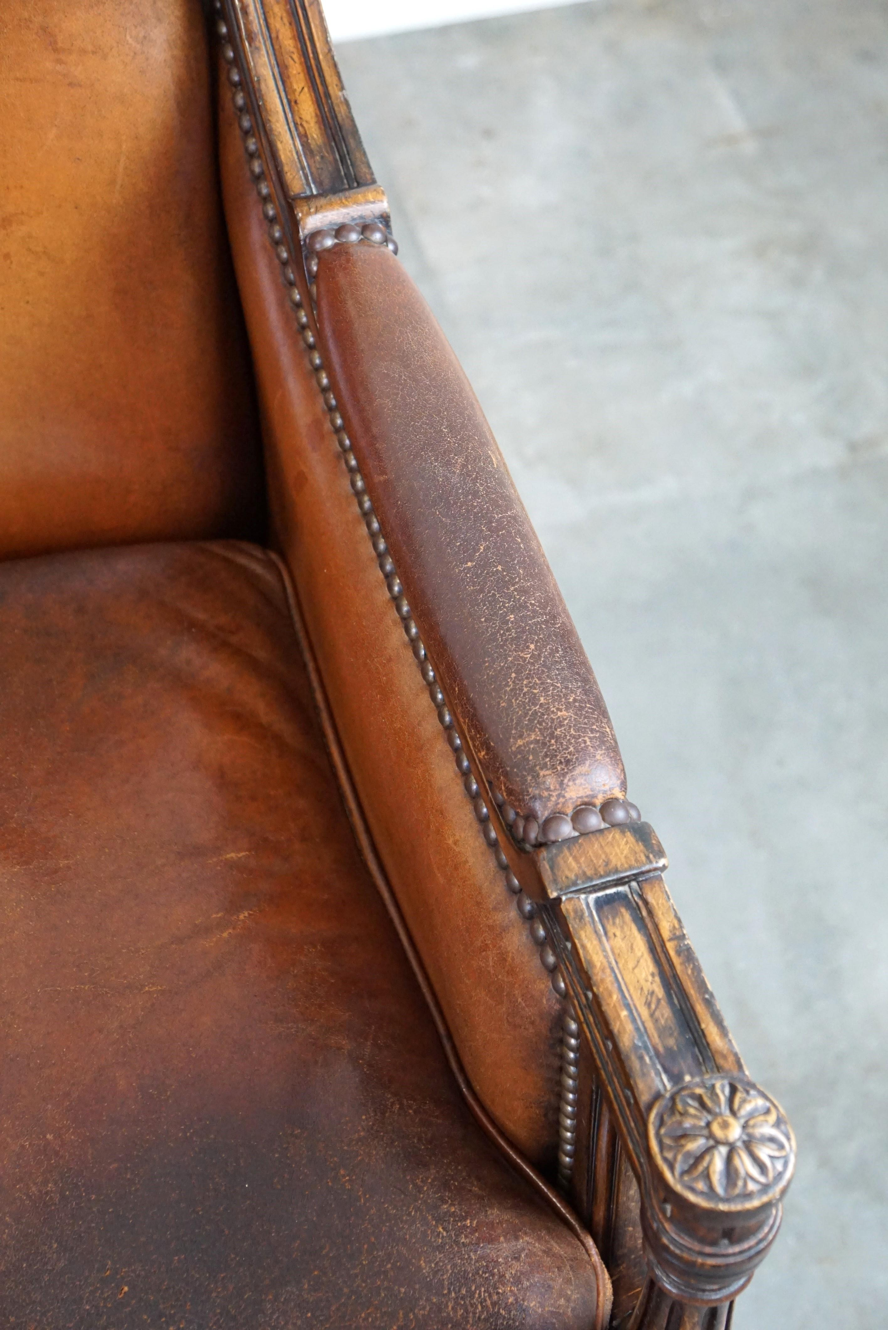 Charmant fauteuil classique en cuir de mouton avec sculptures en bois et belle patine. en vente 1