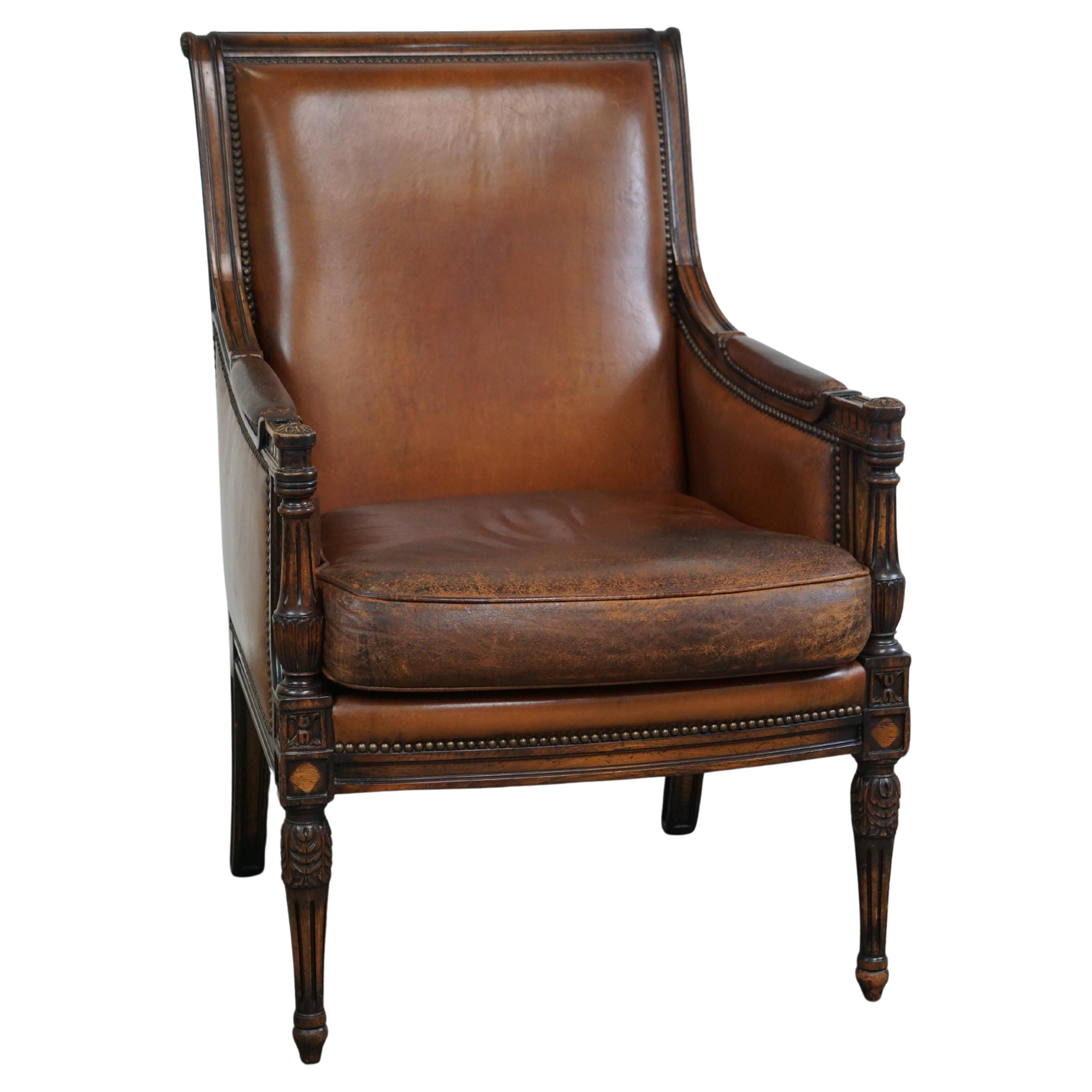 Charming classic sheep leather armchair with wood carving and a nice patina For Sale