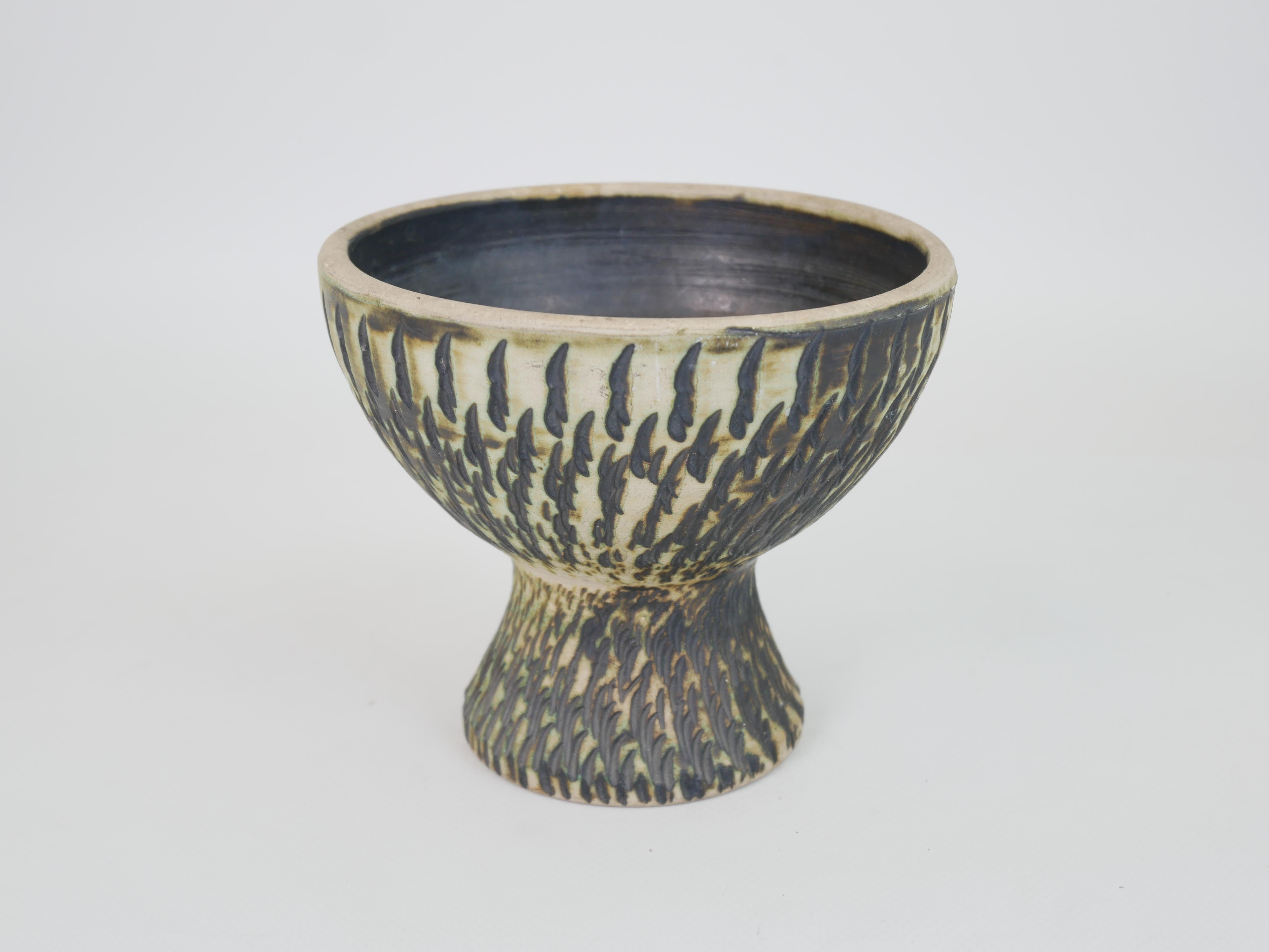 This exquisite 14 cm diameter footed bowl is attributed to Jean Besnard, a pioneer of modern French ceramics. Its striking form features a flared pedestal base supporting a deep, rounded bowl. The surface is decorated with a richly textured
