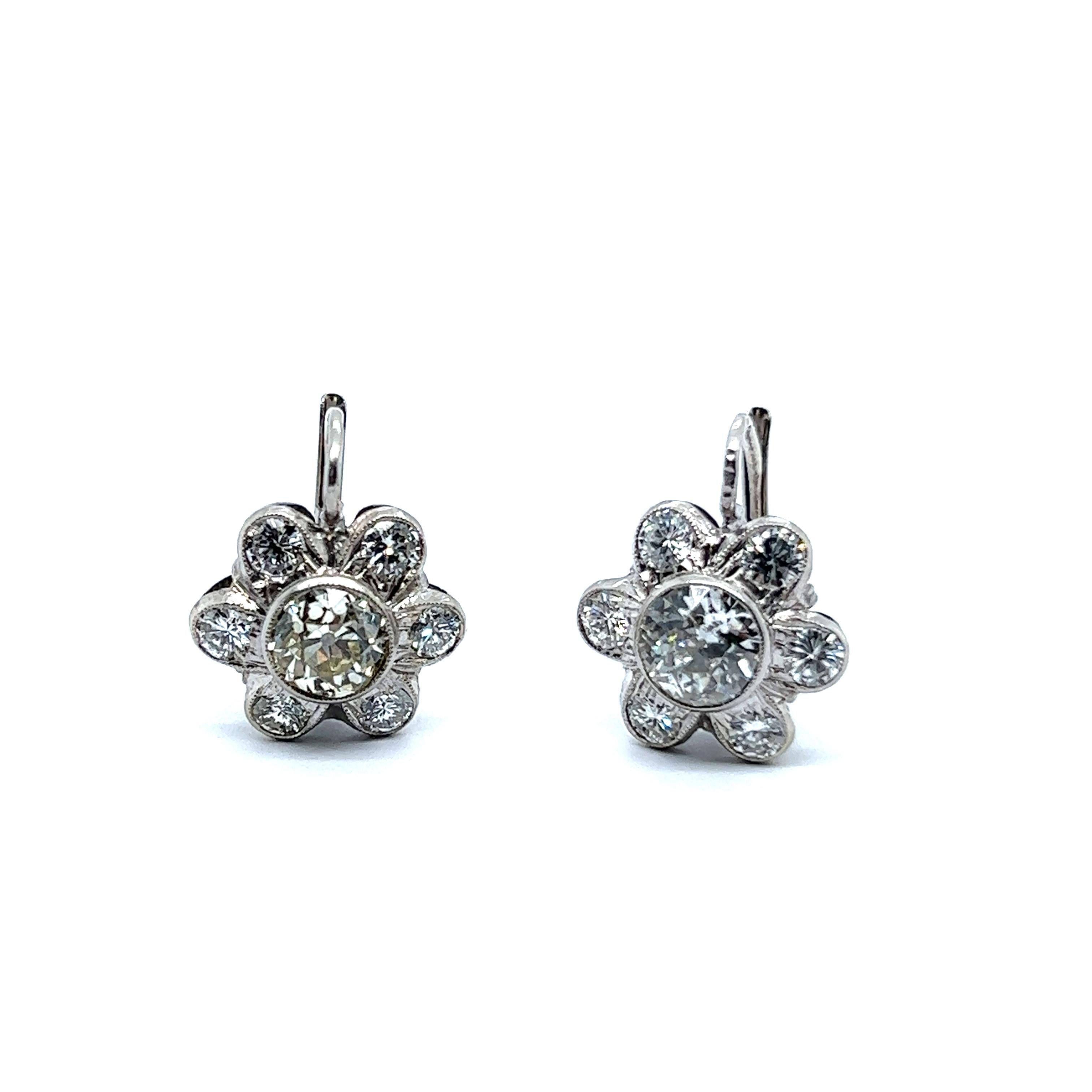 A beautiful embodiment of nature, floral motif earrings in 14 Karat white gold. 

A pair of charming diamond daisies are made in a lovely weave and feature two impressive old cut diamonds at the heart of each flower. One stone is 0.90 carats in M-N