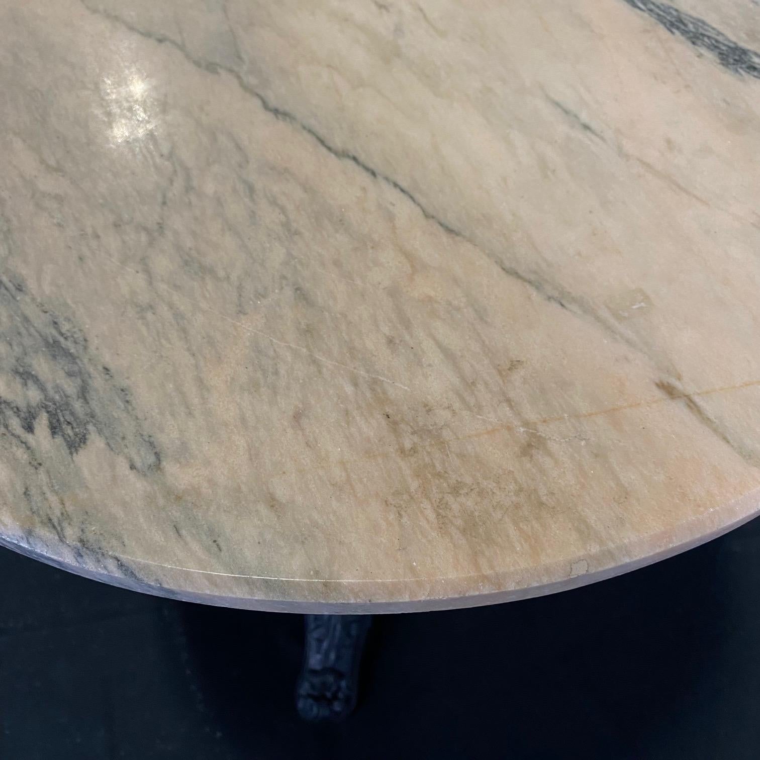 This French round bistro table from the turn of the twentieth century features an iron pedestal base and a really beautiful and substantial pinkish white marble top with gray veining. The marble joins the base with four arm supports. The base is