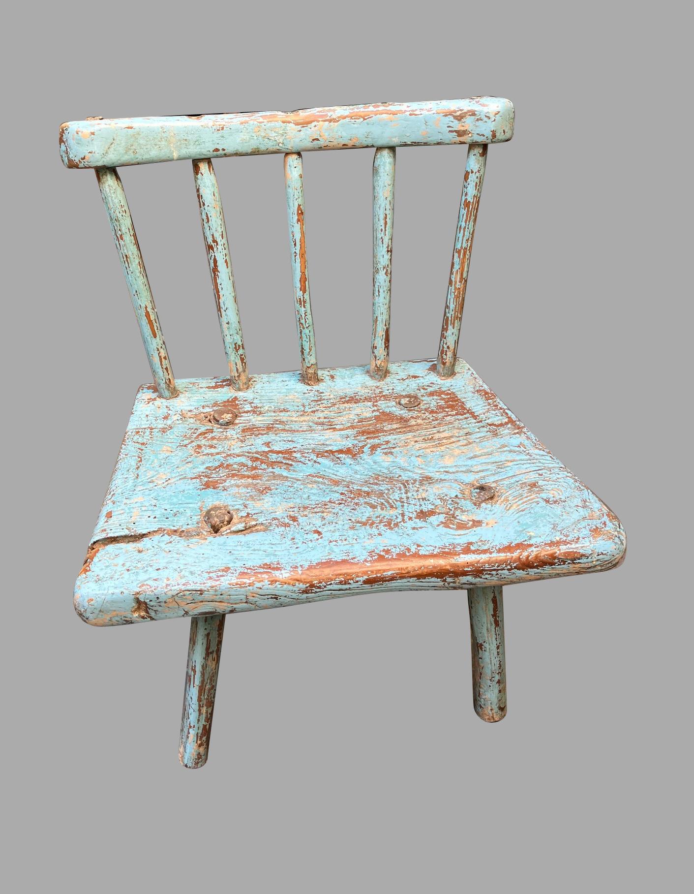 An unusual and charming English provincial child's windsor armchair retaining its original light blue paint, of simple form with a curved crestrail, supported by 5 spindles supported on round legs. One rear leg probably of a later date. Shows