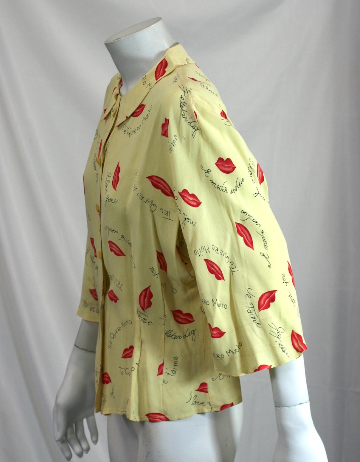 Charming Figural print blouse from the 1940s of pale yellow rayon crepe ground, printed with red pursed lips and various love sayings in different languages.
Dyed mother of pearl buttons. Good Condition.
Length 21