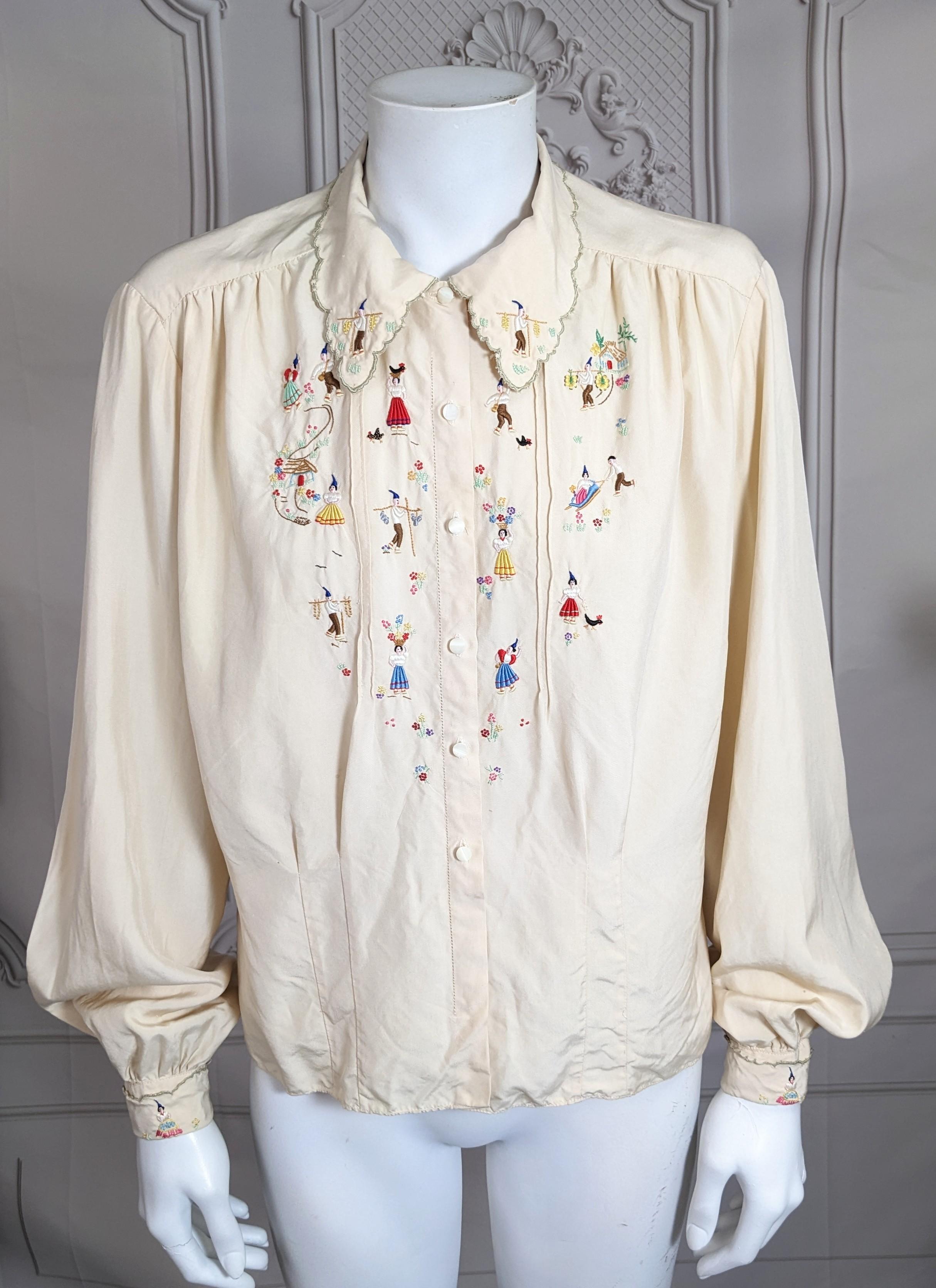 Charmante, folkloristisch bestickte Seidenbluse aus den 1940er Jahren, auf der Dorfbewohner bei der täglichen Arbeit abgebildet sind. Cremeweißes Seidentuch mit Handstickerei und Wellenschliff an Rändern und Manschetten. 1940er Jahre Eu. Winzige