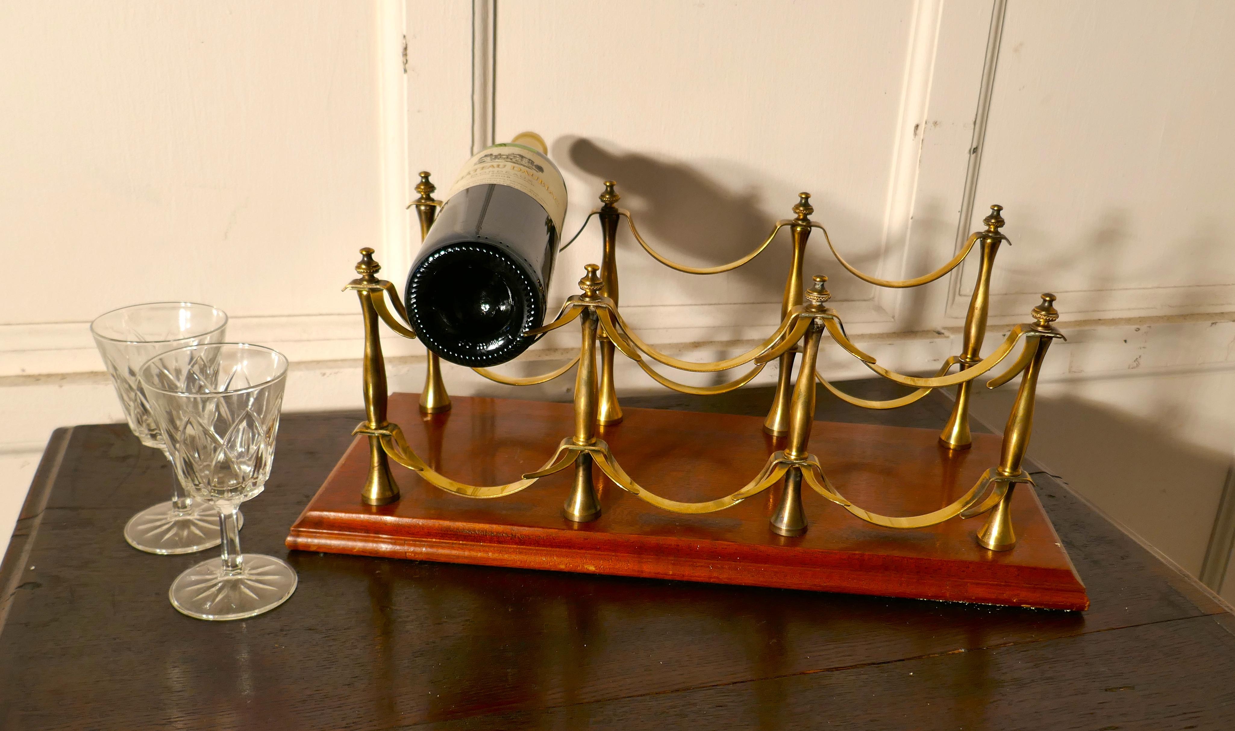 A charming French brass and mahogany sideboard wine rack.

A French tabletop 6 wine bottle rack, on a mahogany base with brass holders.
The wine rack is in excellent condition and both useful as well as attractive.
Measures: The rack is 19”