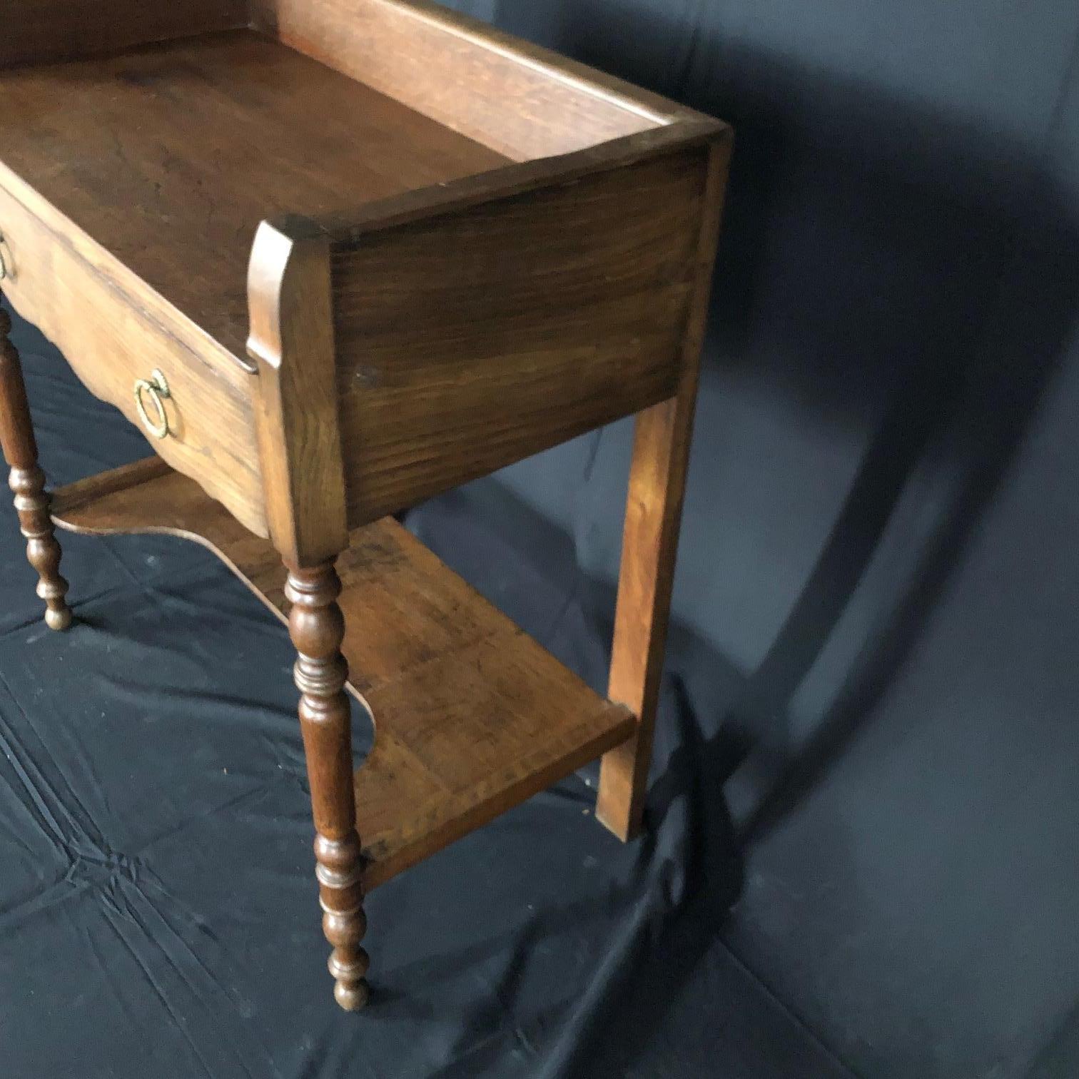 A French oak washstand having full length drawer with bronze pulls and beautifully turned front legs. The lower shelf has a shaped front. Hanging rod on the left side. Functional and beautiful! #5132

Measures: W 31” (28 without left hanging