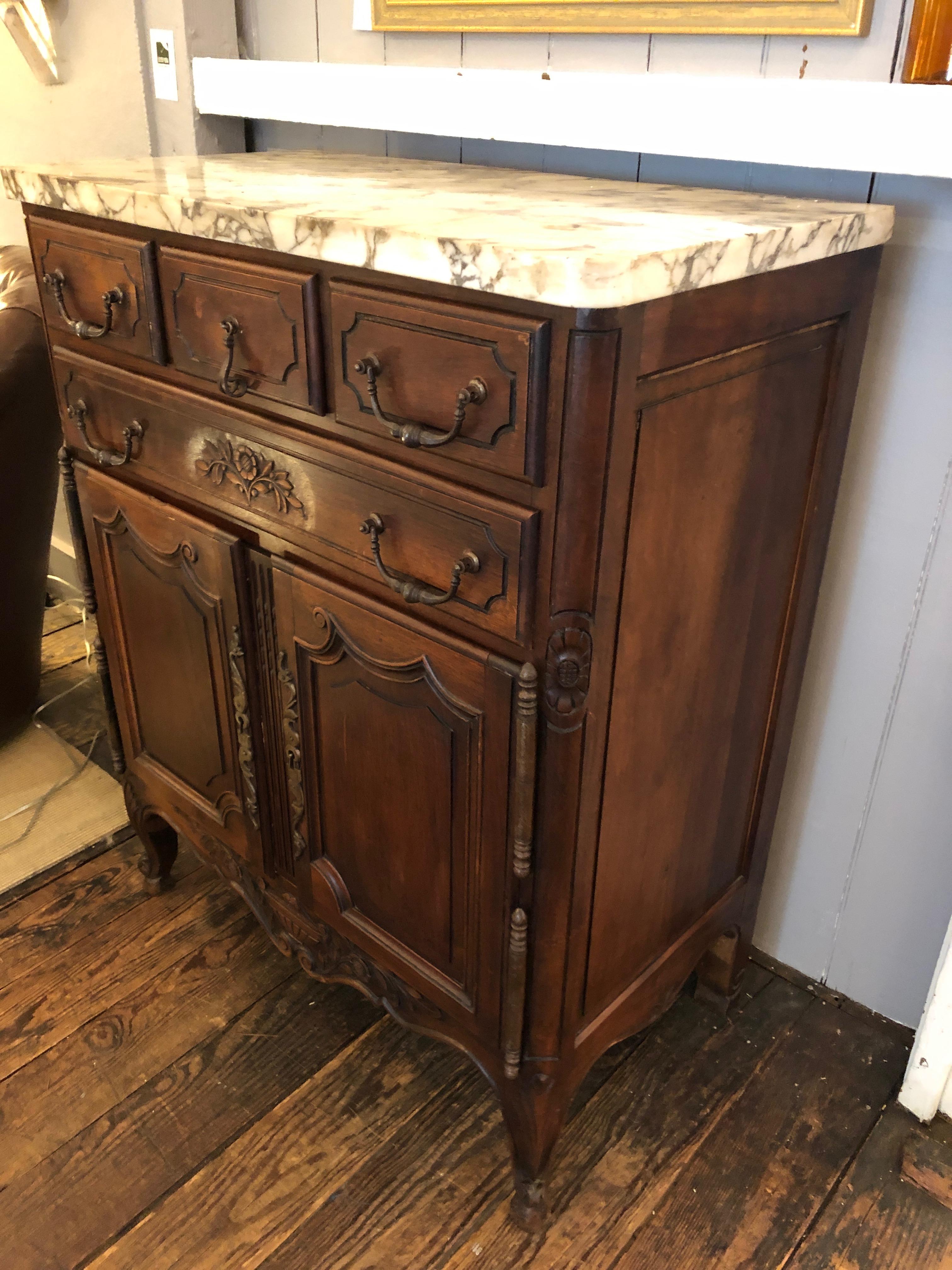 Romantic French carved walnut cabinet having 3 small top drawers with beautiful original hardware, a single drawer underneath, and two panel doors at the bottom section that opens to storage inside. The interior is set up to have shelves; no shelves