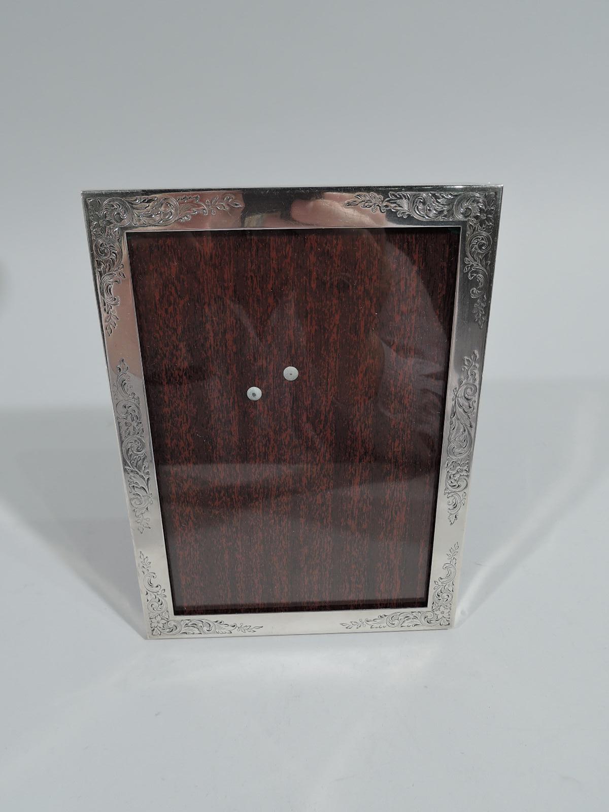 Charming Art Nouveau sterling silver picture frame. Made by Gorham in Providence, circa 1950. Rectangular window and flat surround etched with fluid leafy scrolls and flowers. With glass and laminate back and hinged support. For portrait (vertical)