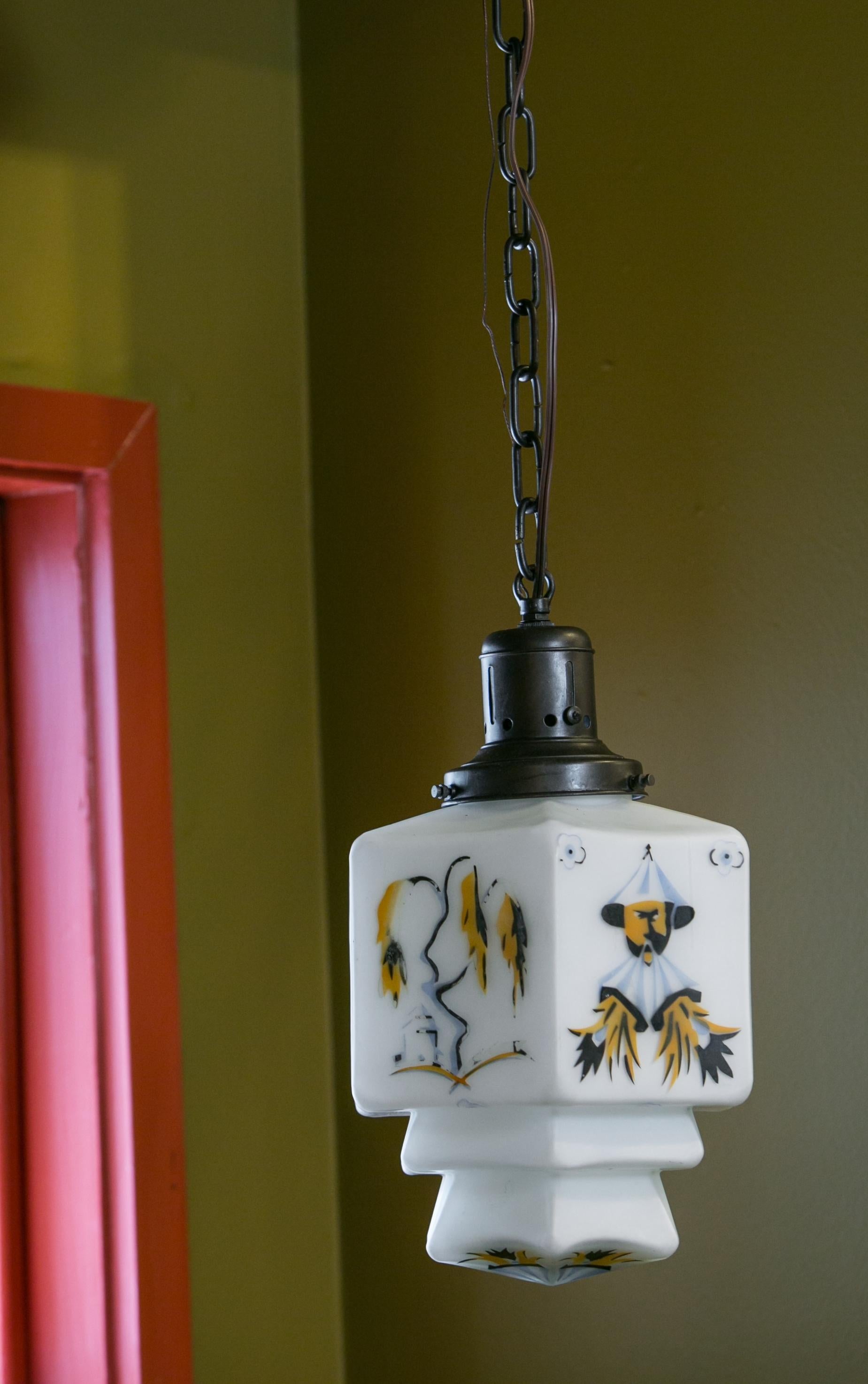 This funny little matte milk glass pendant has been panted with Chinoiserie images. It has been handblown and hand-painted.

It is all original except for newly added chain and a check ring added to the vintage canopy in order to make it ready to