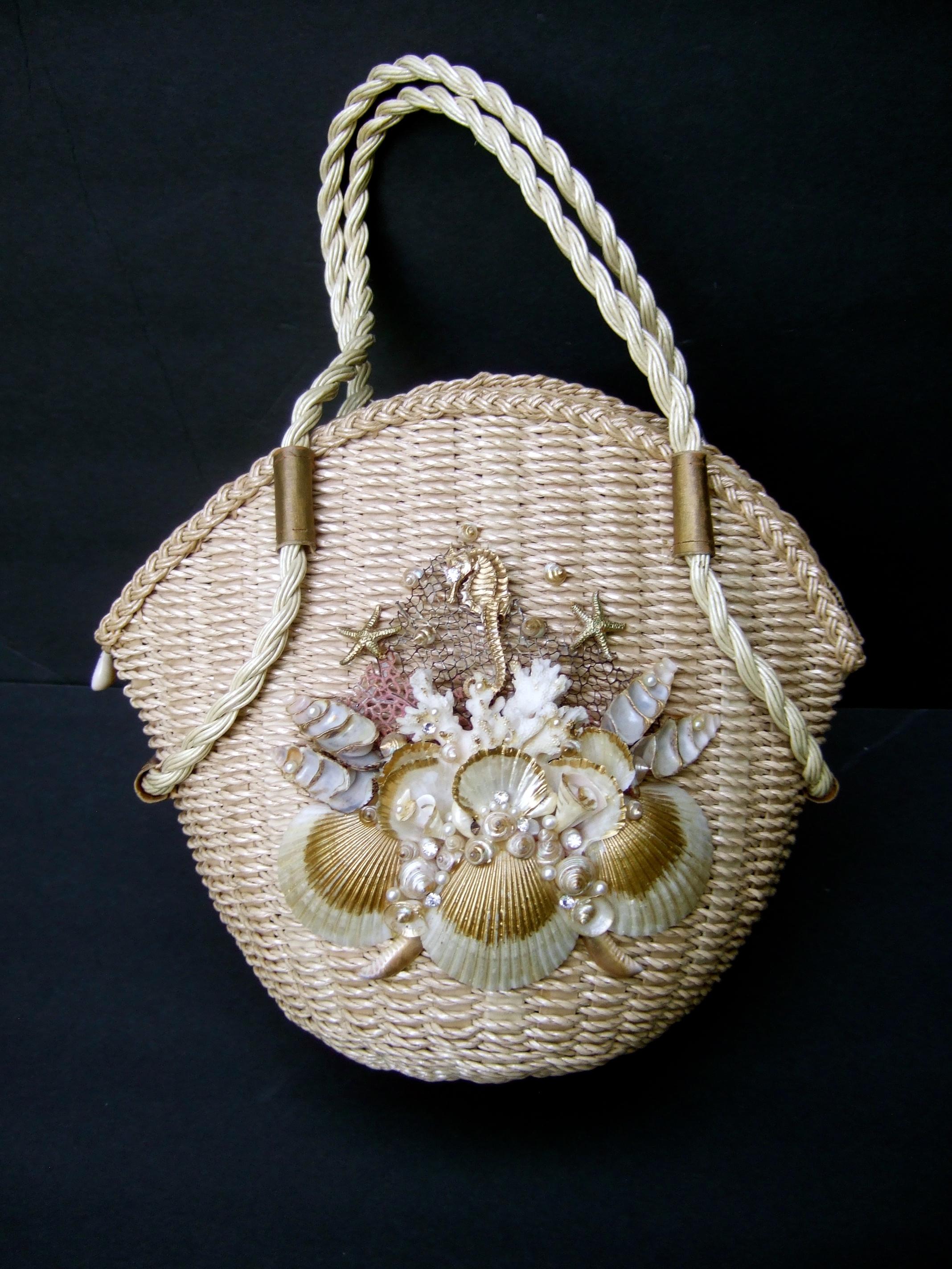 Charming handmade artisan woven wicker rattan rope vintage basket style handbag. Embellished with a cluster of organic sea shells with gold enamel accents; with small resin enamel pearls & small diamante crystals . Carried with a pair of braided