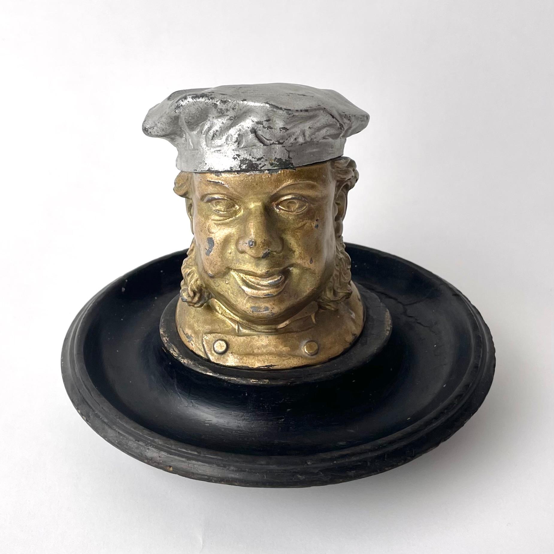 Charming Ink Well/Inkstand in the shape of man's head, painted white metal and patinated wood. Made in England during the 19th century.

A simply charming inkstand consists of a a painted wood-turned base upon which is mounted a white metal inkwell