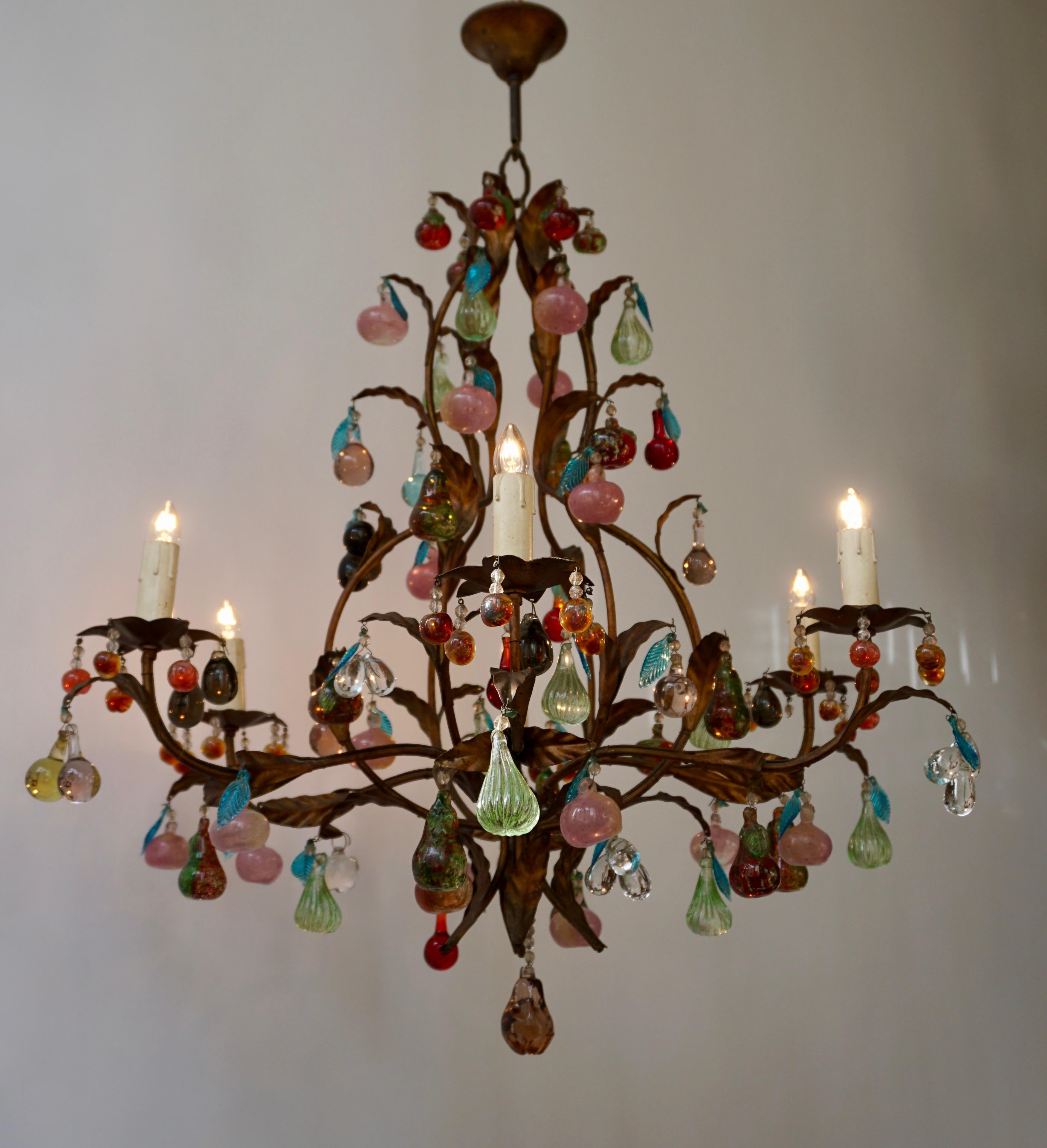 Charming Italian brass and Murano glass chandelier embellished with fruit pendants and drops in colored glass.
The different fruits, like grapes, pears and apples, in solid Murano glass are and also the molded leaves present sumptuous colors.