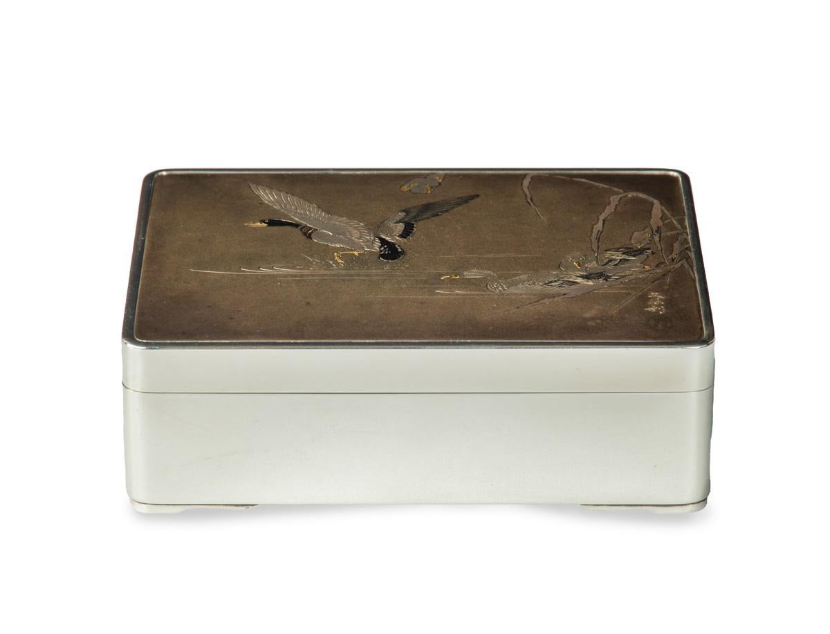 As part of our Japanese works of art collection we are delighted to offer this Meiji Period 1868-1912, pure silver and mixed metal table box artist signed Bunkei aside a gold seal. The box is formed from pure silver and rests upon bracket feet , the
