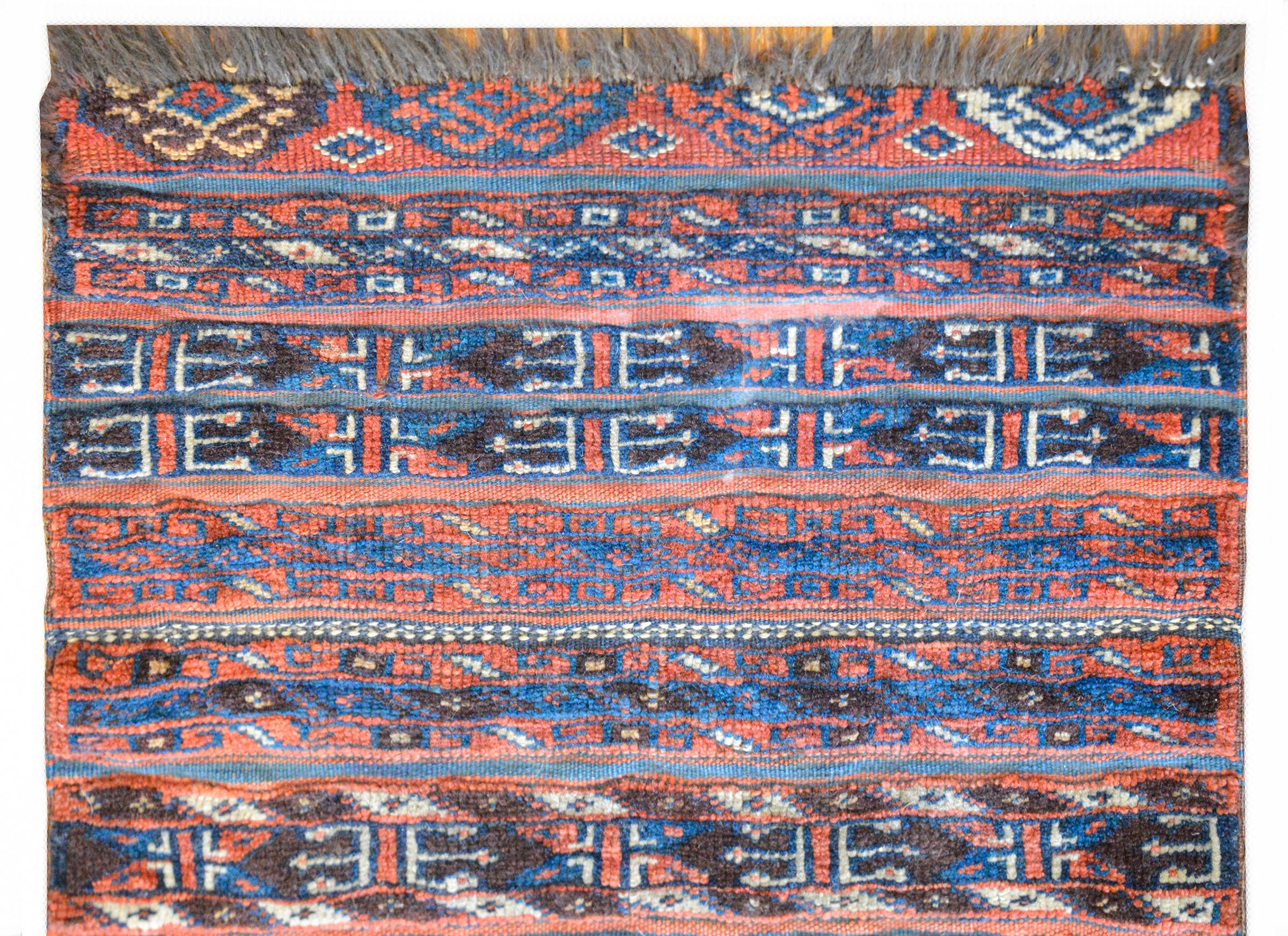 Un affascinante tappeto persiano turkmeno della fine del XIX secolo con un bellissimo motivo a strisce geometriche tessute in lana cremisi, indaco, bianco e marrone.