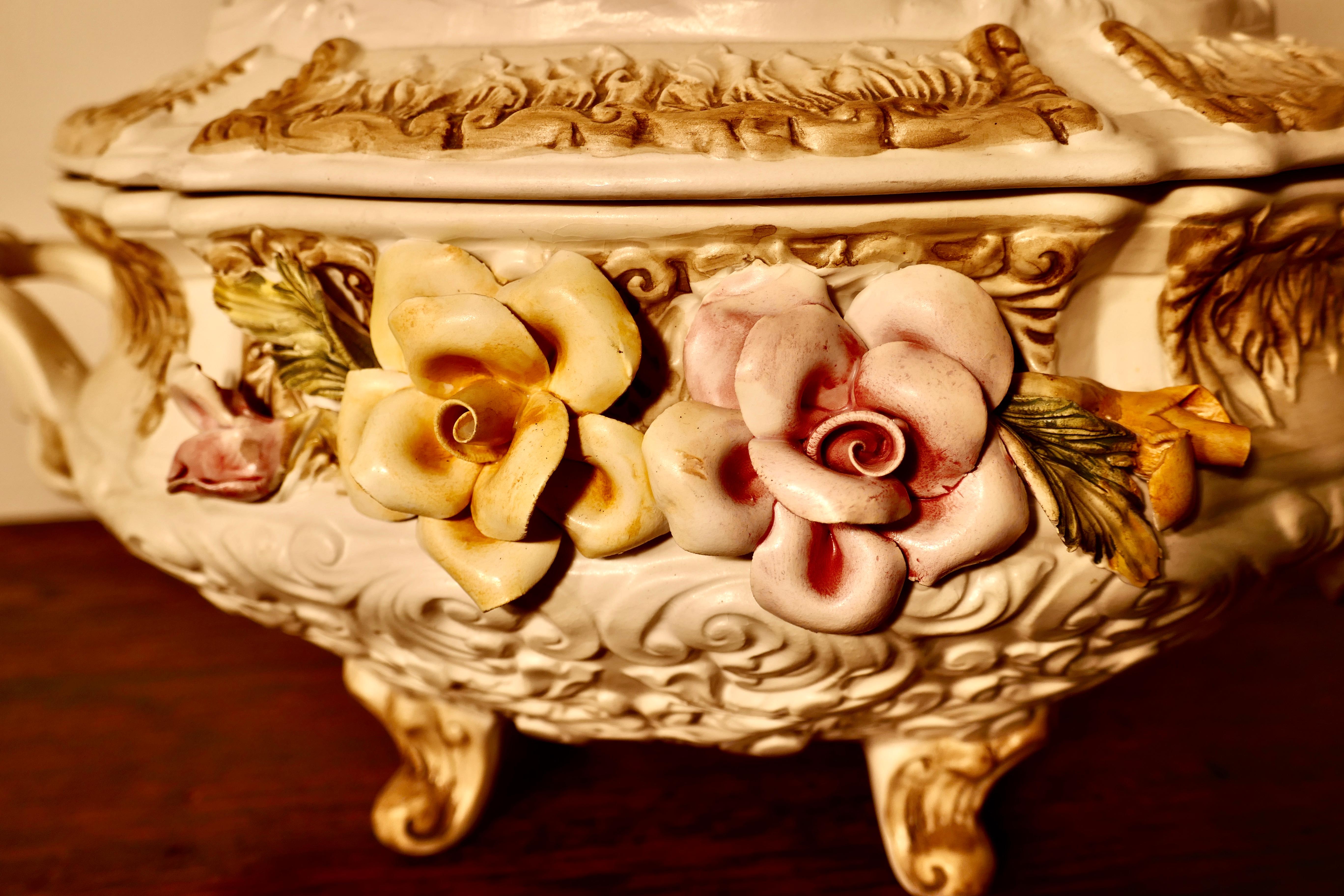 Charming late 20th century Capodimonte tureen with lid

A delightful piece all fully marked beneath, the lid has 2 children on the top and the bowl has handles and the trademark bocage and flowers on the front
Not new but as far as we can see no
