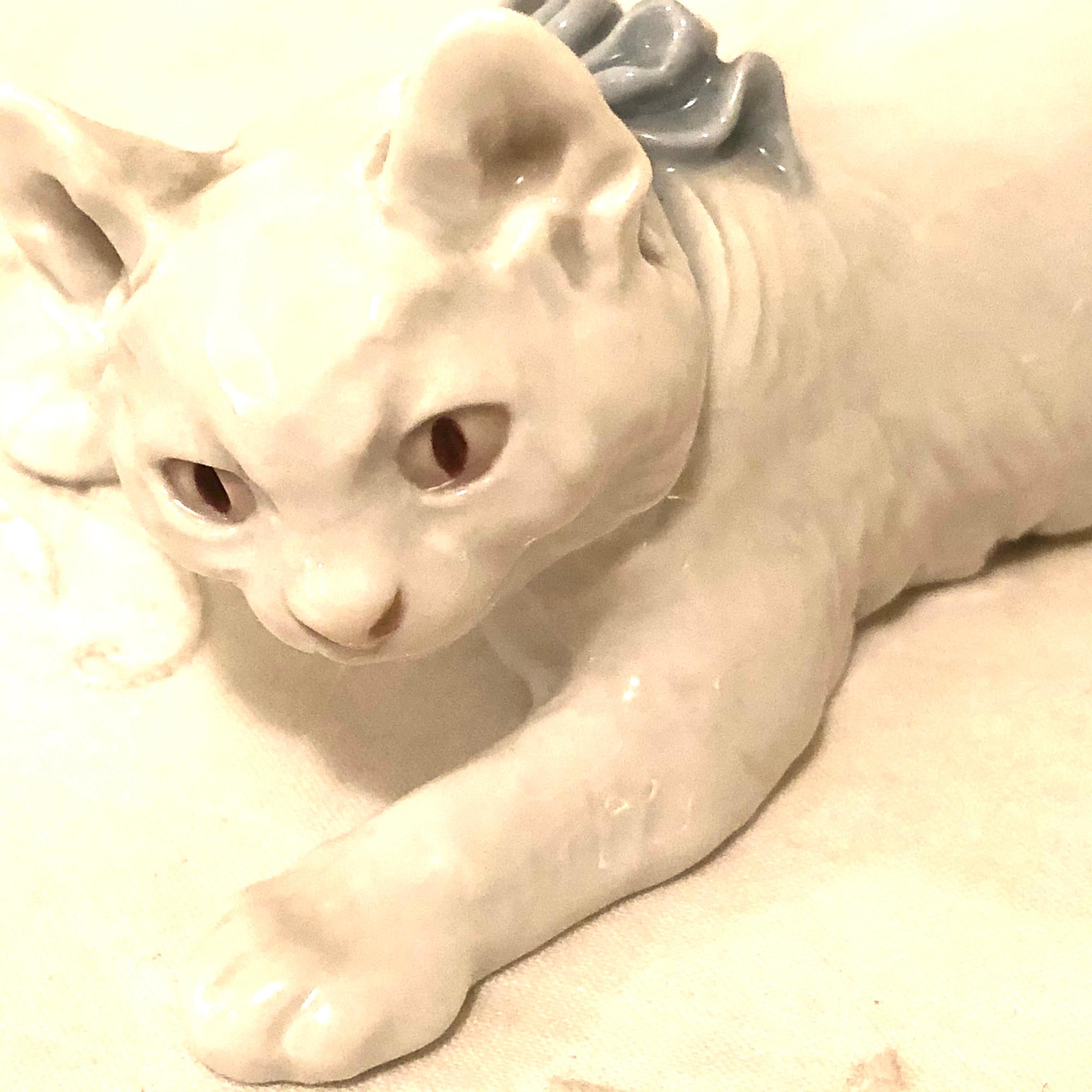 Charming Meissen figure of a finely modeled white cat with a blue bow. The cat looks like he is playing, as he is leaning forward with his long white tail in the air. You can see how realistic his eyes, ears and paws were made. This enchanting