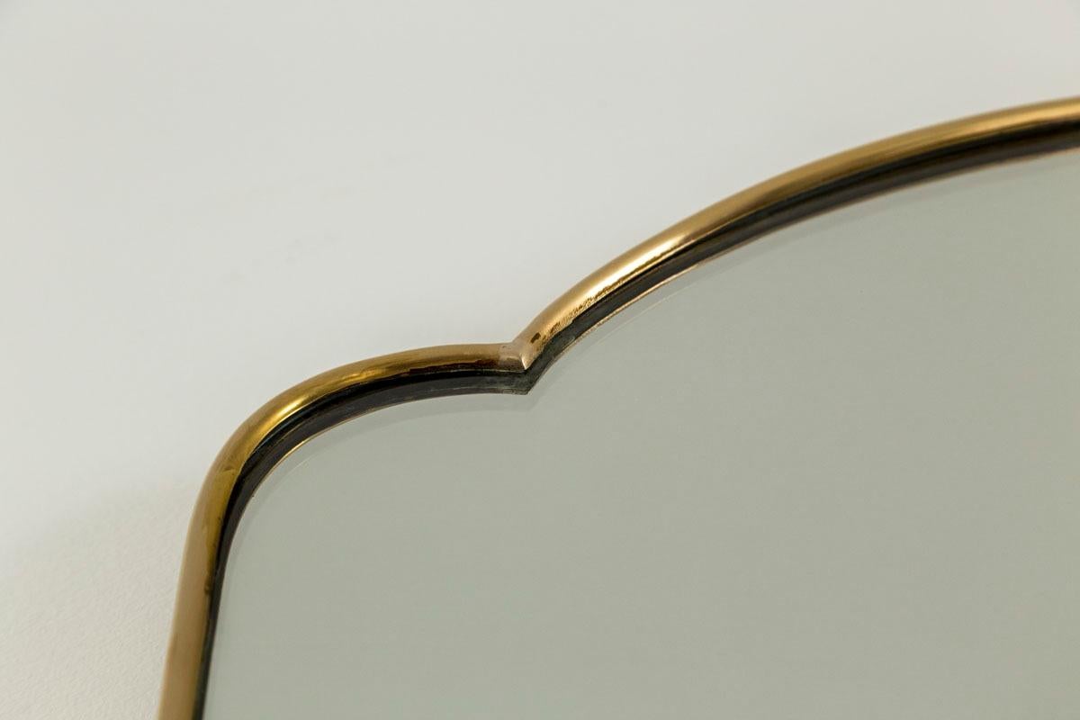 Una tripla bombatura elegante e stravagante  e specchio affusolato con cornice in ottone non laccato e schienale in legno composito.  
L'ottone è stato lucidato di recente e il vetro è originale e in ottime condizioni.
 