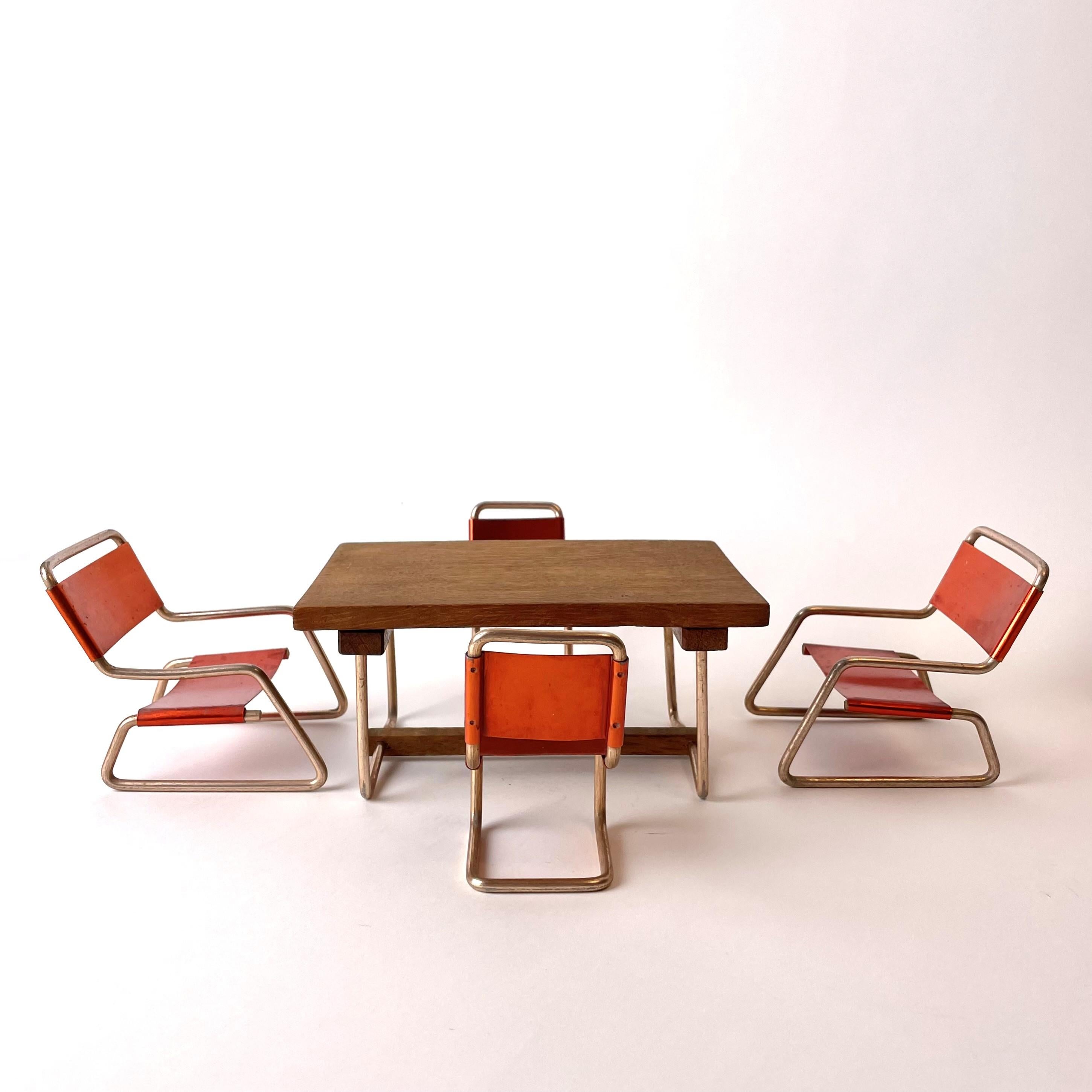 Charmante Miniatur-Sitzgruppe aus Aluminium und mit einer Tischplatte aus Teakholz. Hergestellt in den 1930er-1940er Jahren im zeittypischen Bauhaus-Stil.

Maße: Die ganze Gruppe, angeordnet wie auf den Fotos, etwa 42cm*28cm*10cm.
Tisch: