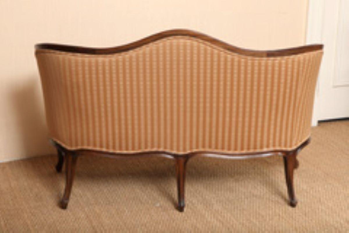 Add style and comfort with this charming old French Hepplewhite style upholstered settee with molded serpentine shaped-wood frame. The elegant serpentine shaped back and seat brings a pleasing feel to any room. The lovely floral carving to the front