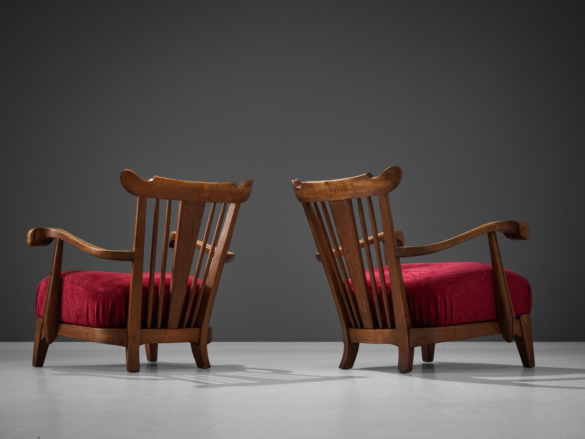 Pair of armchairs oak, velvet, France, 1950s.

These beautifully designed lounge chairs hold a striking construction by means of the sculpted elements discernible in the wooden frame. The armrests are characterized by curved, strong lines with
