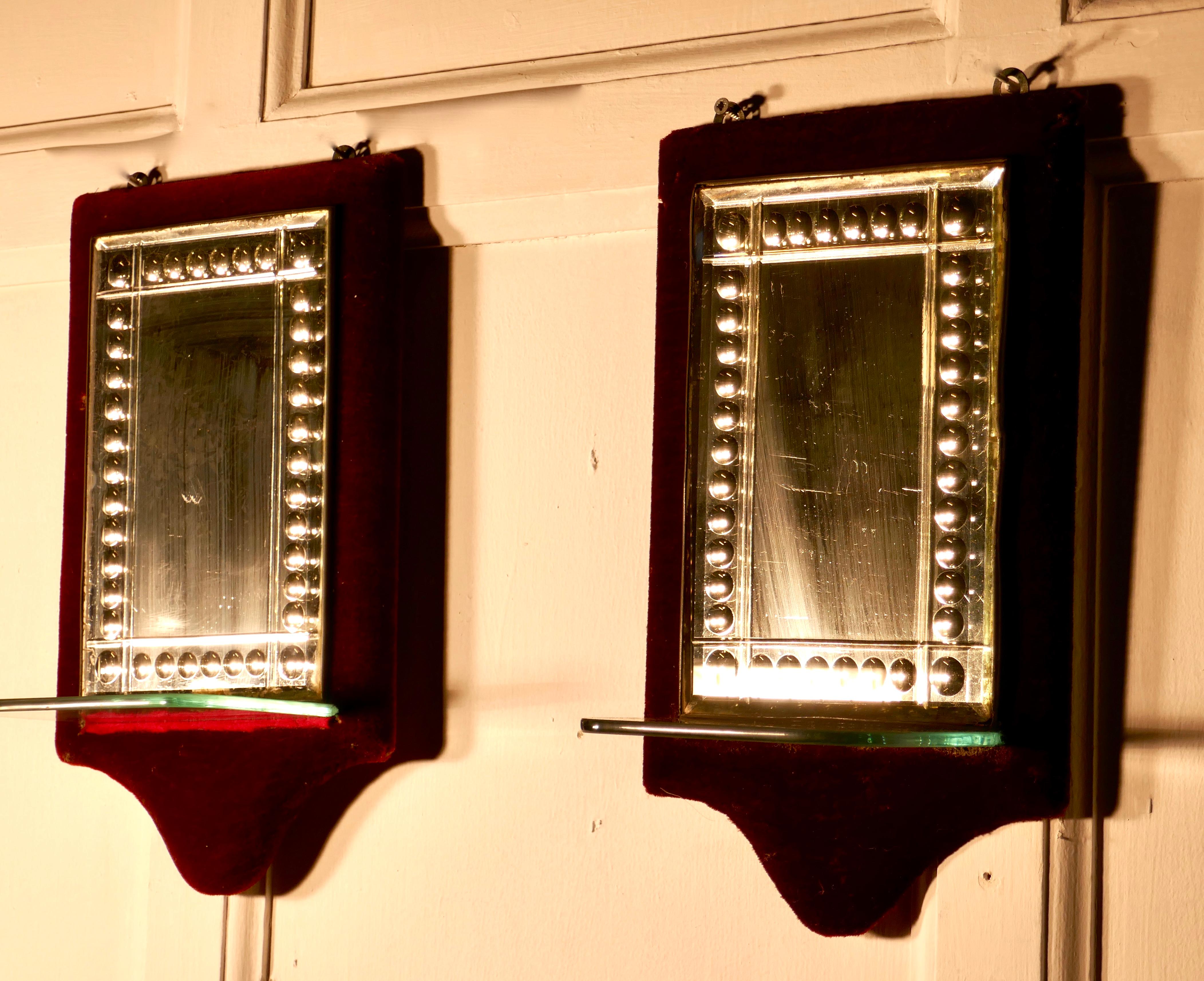 Charming pair of French red velvet boudoir shelved wall mirrors

Pretty pieces, the mirrors have a decorative etched glass border, they are set on dark red velvet, with a small glass shelf 
The mirrors are sound with some age related foxing and