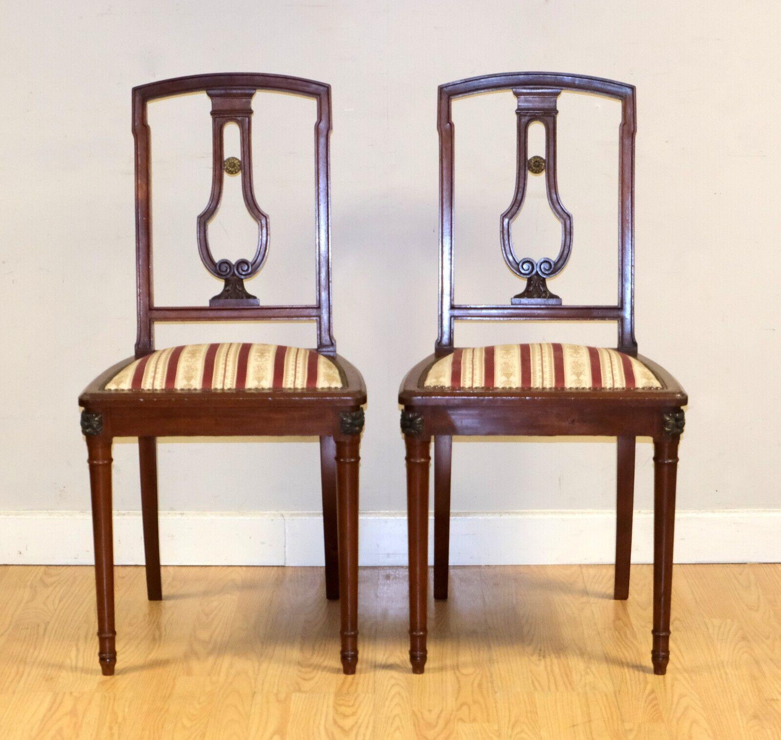 Siamo lieti di offrire in vendita questa splendida coppia di sedie d'epoca con seduta in tessuto.

Questa coppia di sedie poggia su gambe affusolate con dettagli distinti agli angoli. La seduta ha un bel disegno in tessuto rosso e bianco con borchie