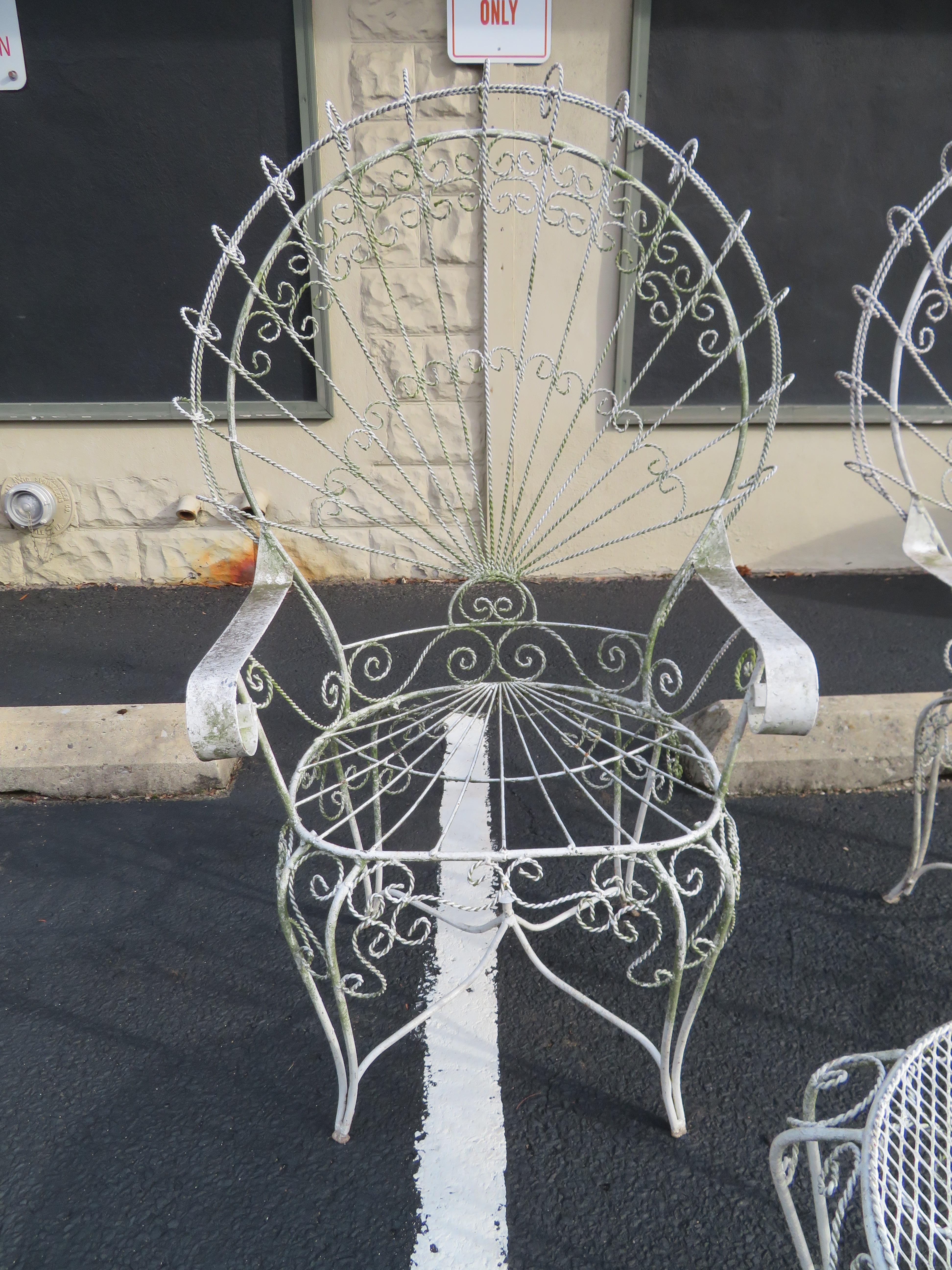 Gorgeous pair of Salterini ornate wrought iron twisted wire fan back patio chairs with matching side table. This pair will have a new coat of white paint before they are shipped. There are no cracks or breaks to the frames-sturdy.