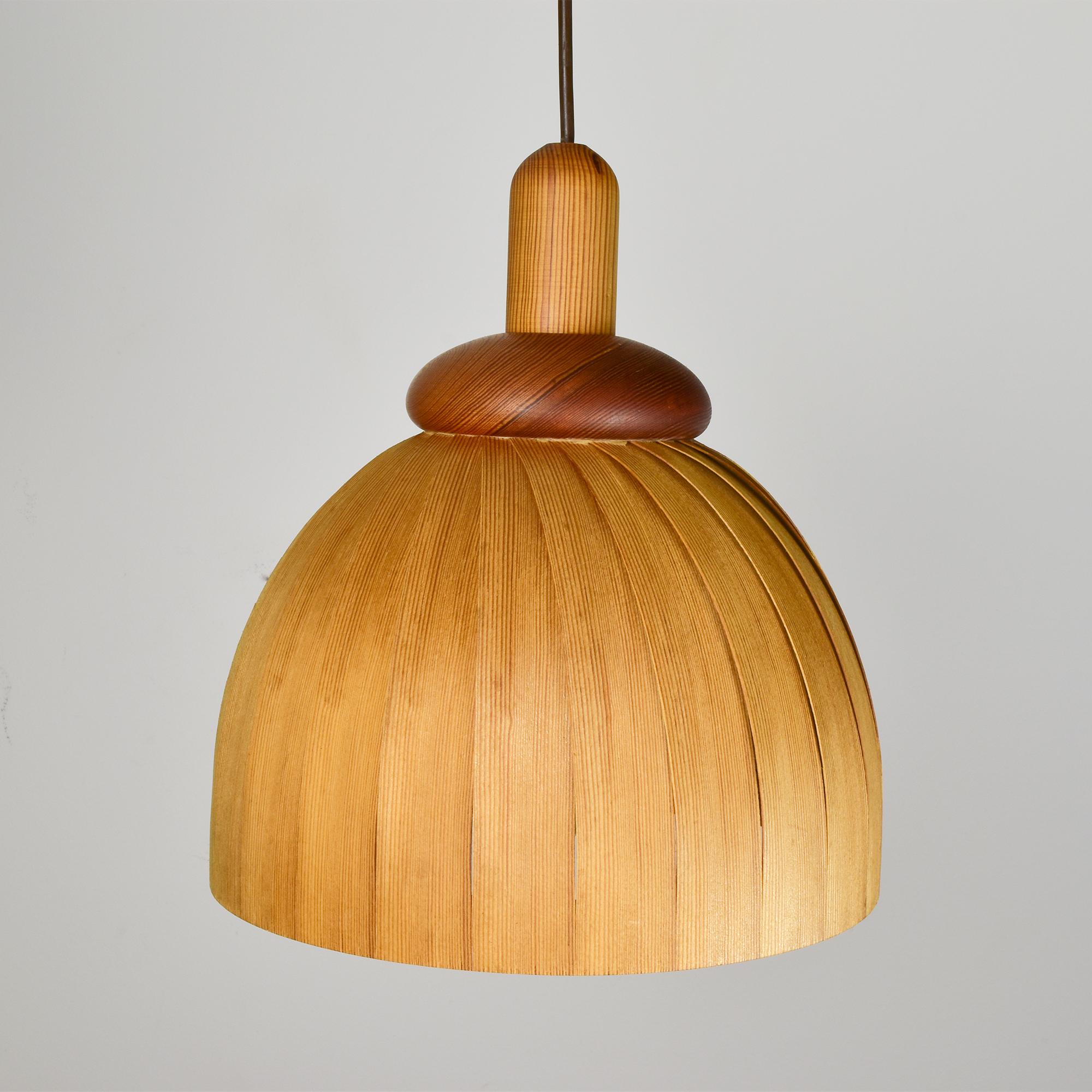 Questa affascinante lampada a sospensione, disegnata da Hans-Agne Jakobsson e prodotta da Ellysett, incarna l'essenza del design scandinavo. Realizzata negli anni '70, questa lampada presenta una splendida silhouette curva in legno di pino, che