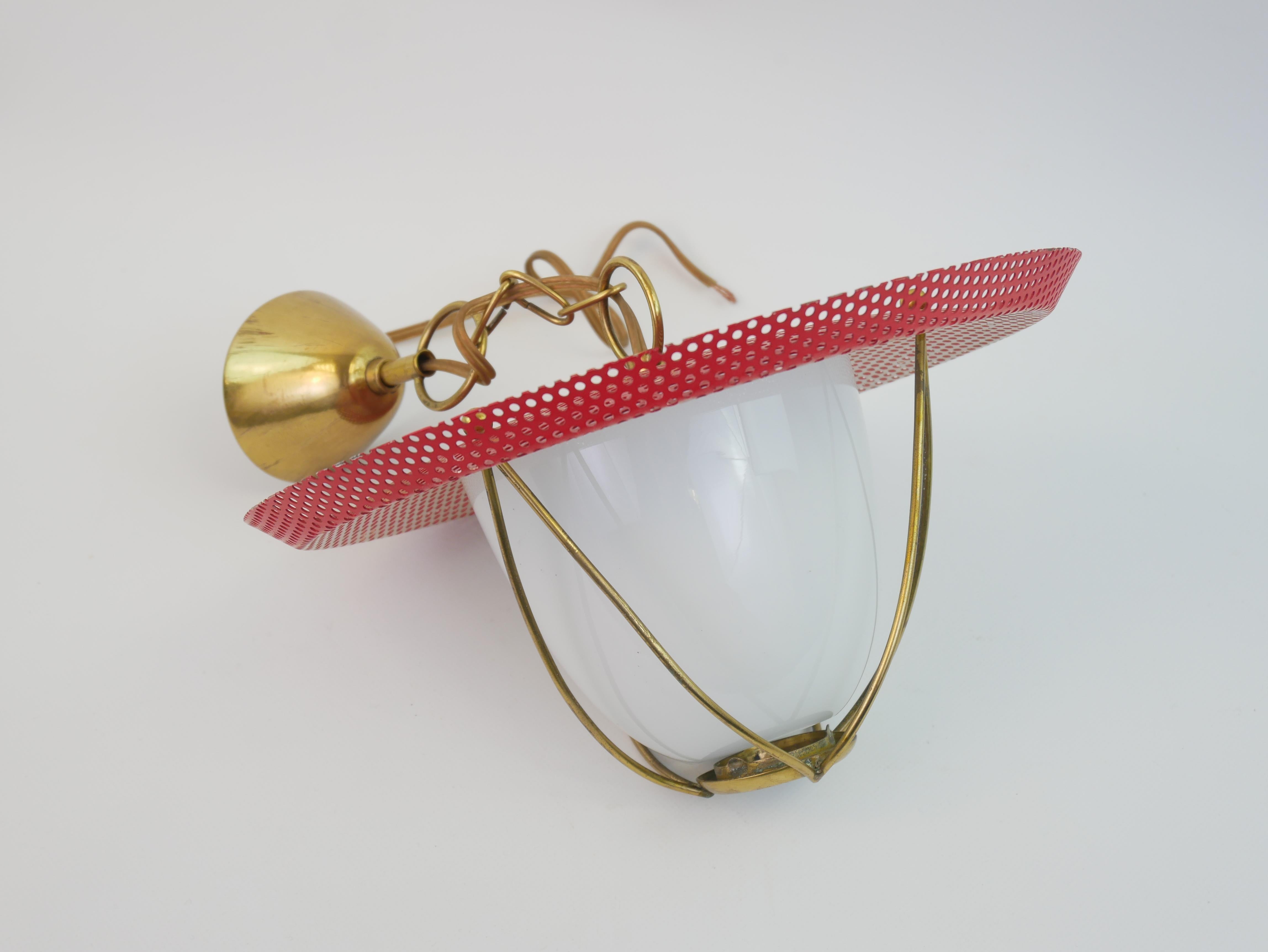 Questa lampada a sospensione combina eleganza e funzionalità con un'estetica moderna di metà secolo, che ricorda lo stile di Mathieu Matégot. Realizzato in ottone, metallo laccato traforato rosso e vetro opalino, emana un fascino raffinato ma