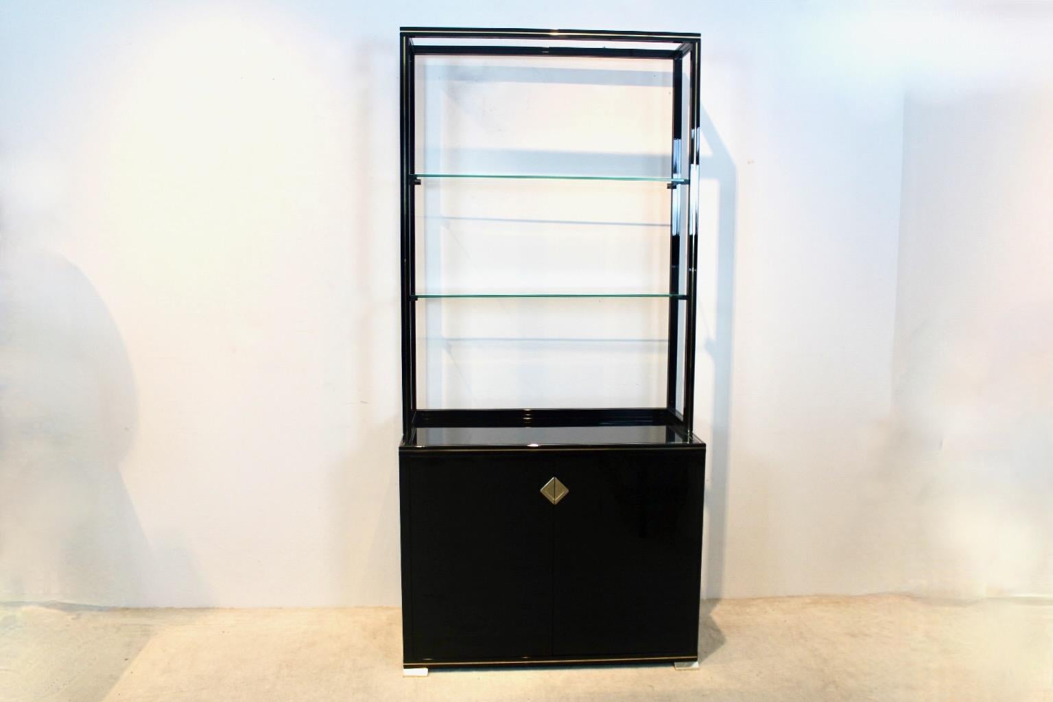 Charming Pierre Vandel Paris black lacquered French Cabinet with stylish gold trim and handles. The unit has a small sideboard base with two doors and a removable upper part with shelving and display function, coming with two glass tiers (no chips