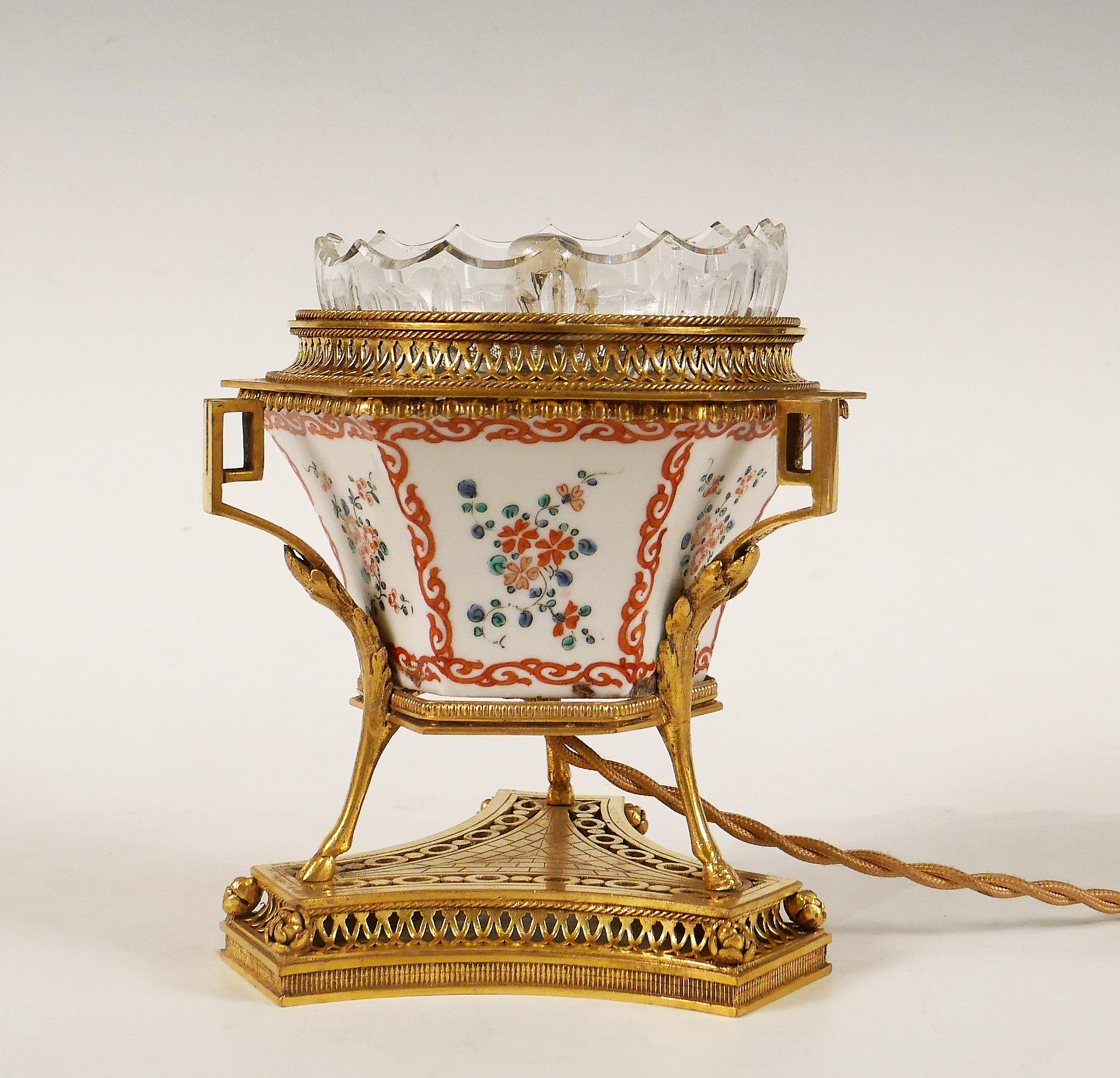 Height : 15 cm (5,9 in.) ; Diam. : 15 cm (5,9 in.) ; Base width : 12 cm (4,7 in.)

Charming hexagonal night light in painted porcelain decorated with flowers, surmounted by an openwork gallery in gilded bronze containing a cut crystal corolla.