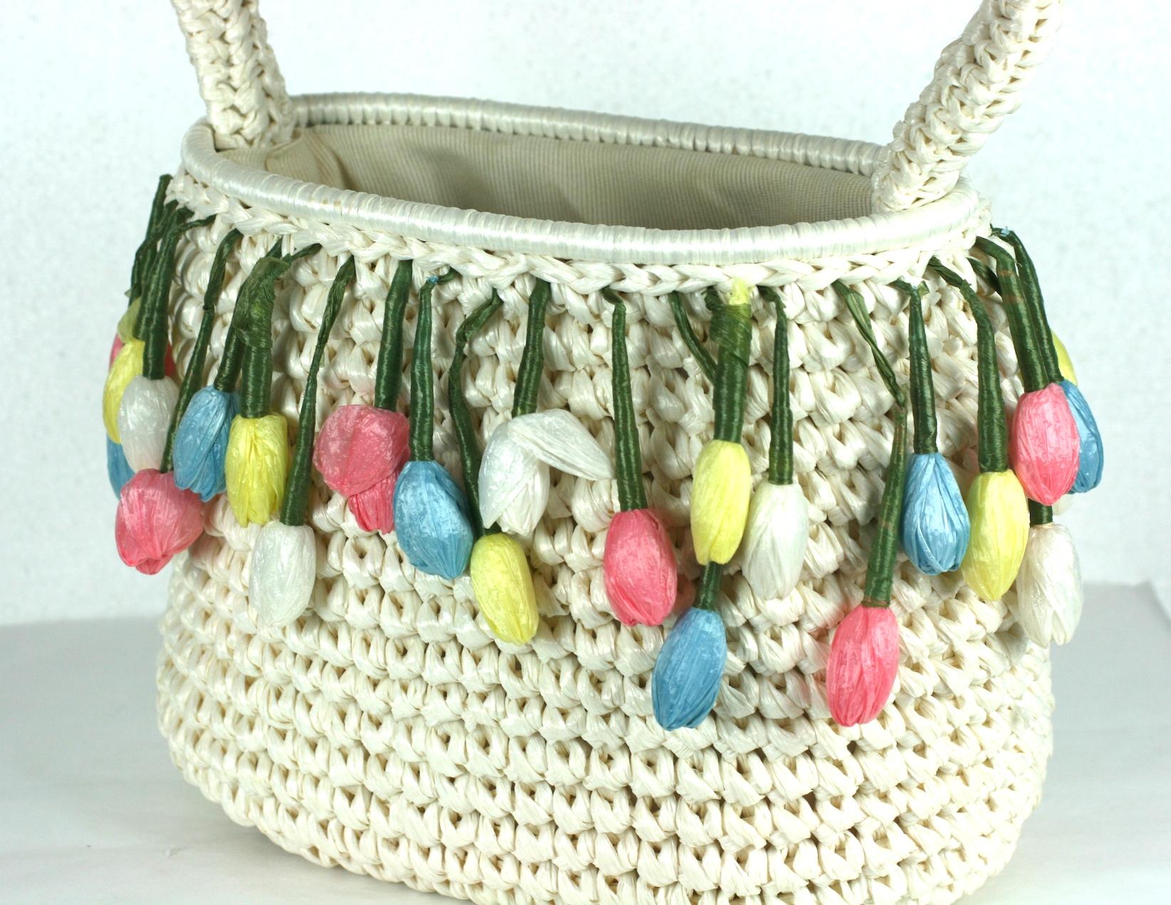 Charming Raffia Tulips Handbag from the 1960's. Ivory cellophane raffia is crochet to form the body of the open top bag. A fringe of handmade pastel raffia tulips decorates the upper edge. Handle adds 5
