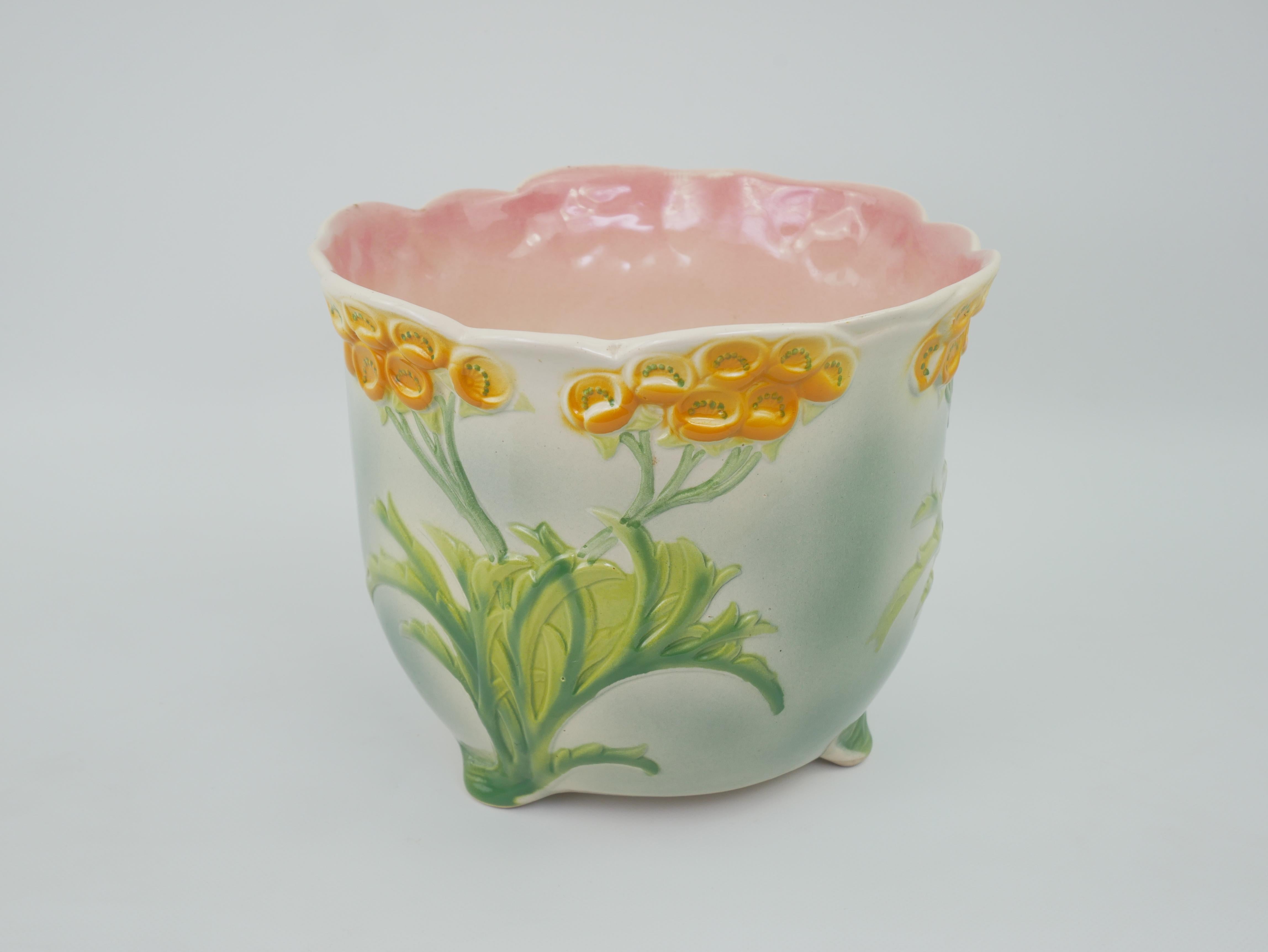 Ce cache-pot décoratif est un bel exemple de céramique française de Barbotine, fabriquée par la célèbre manufacture de Saint-Clément. Il présente un design vibrant inspiré de la Nature, avec des motifs floraux en haut-relief. L'extérieur présente