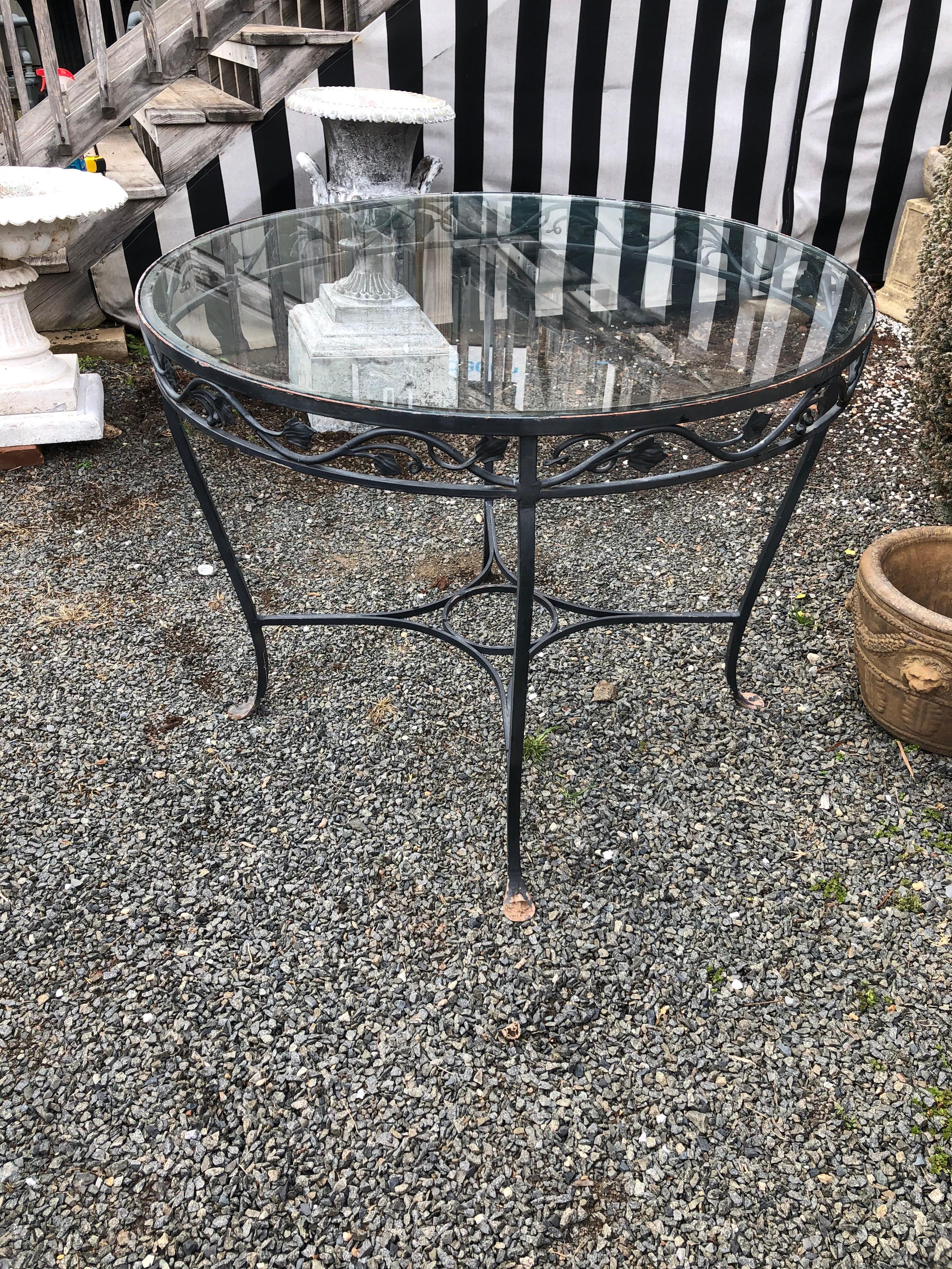 Classic round Salterini black wrought iron garden table with leaf motife and glass top.
