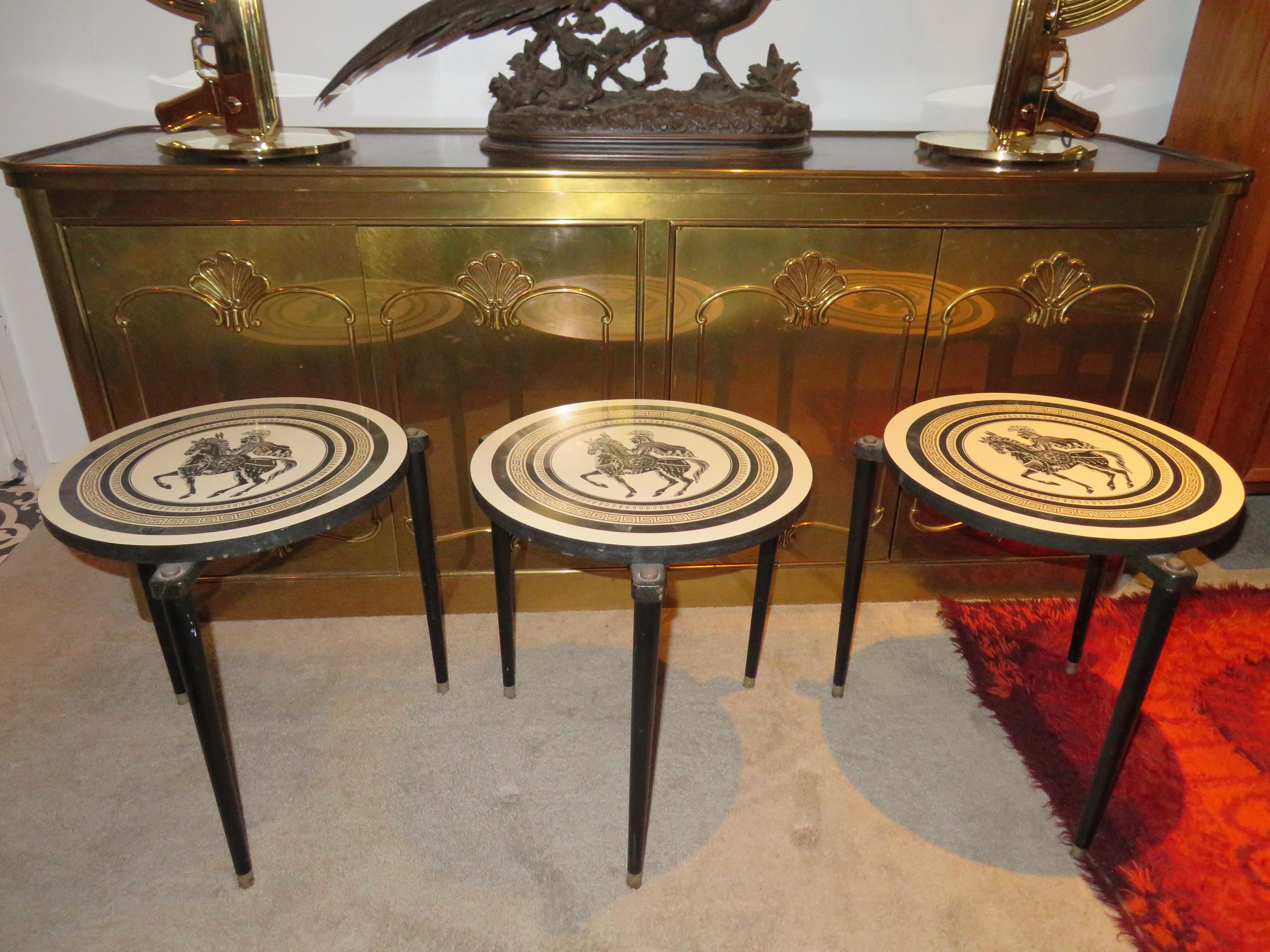 Charming set of 3 Piero Fornasetti style stack nesting tables. The formica table tops each have a stylized Greek soldier on horseback with Greek key borders. Each table measures 17.5