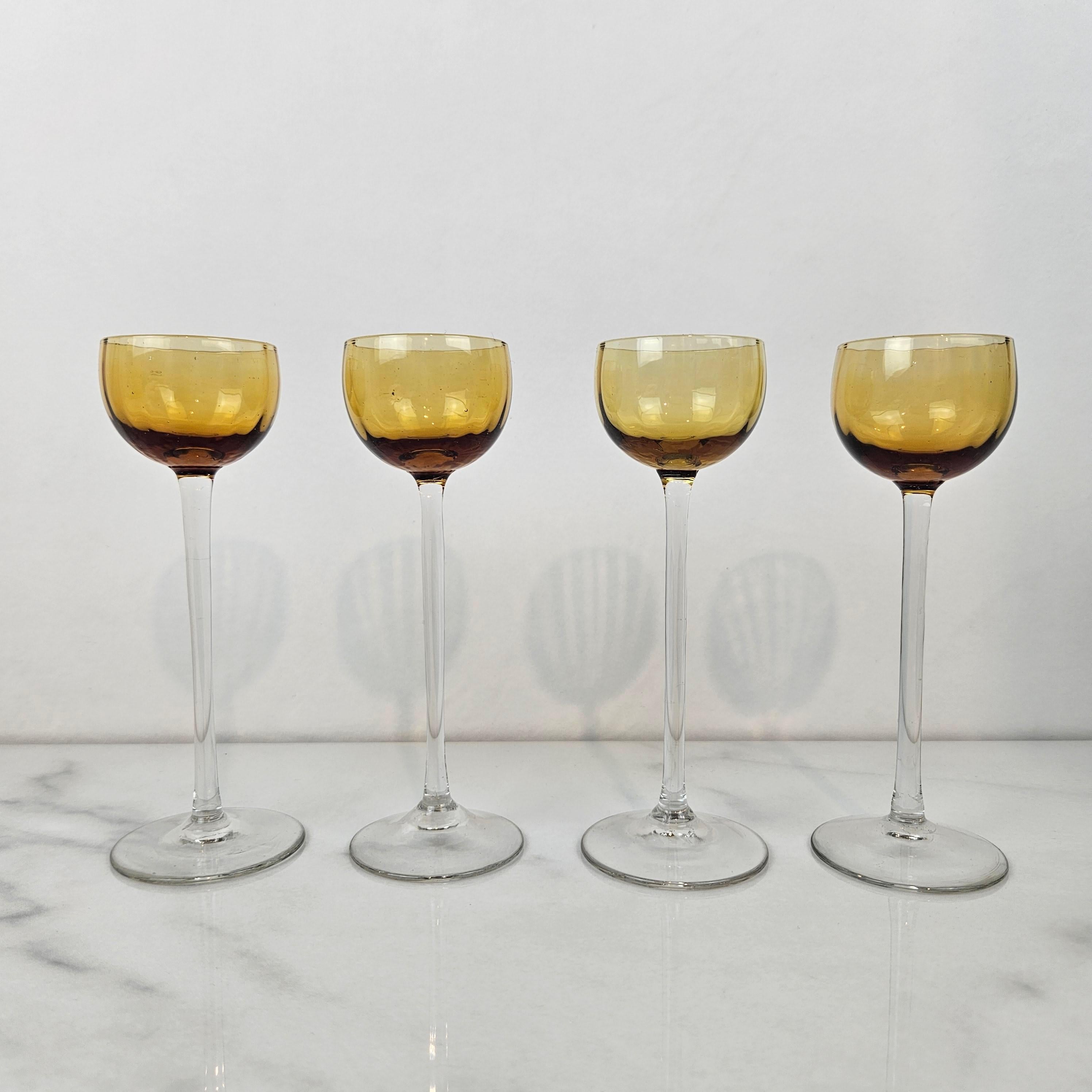 Un magnifique et rare ensemble de quatre verres à liqueur ou à cordial anciens, soufflés à la main et datant d'environ 1920. 
Chaque verre présente un bol ambré légèrement nervuré et une longue tige droite - une forme élégante et allongée, à la fois