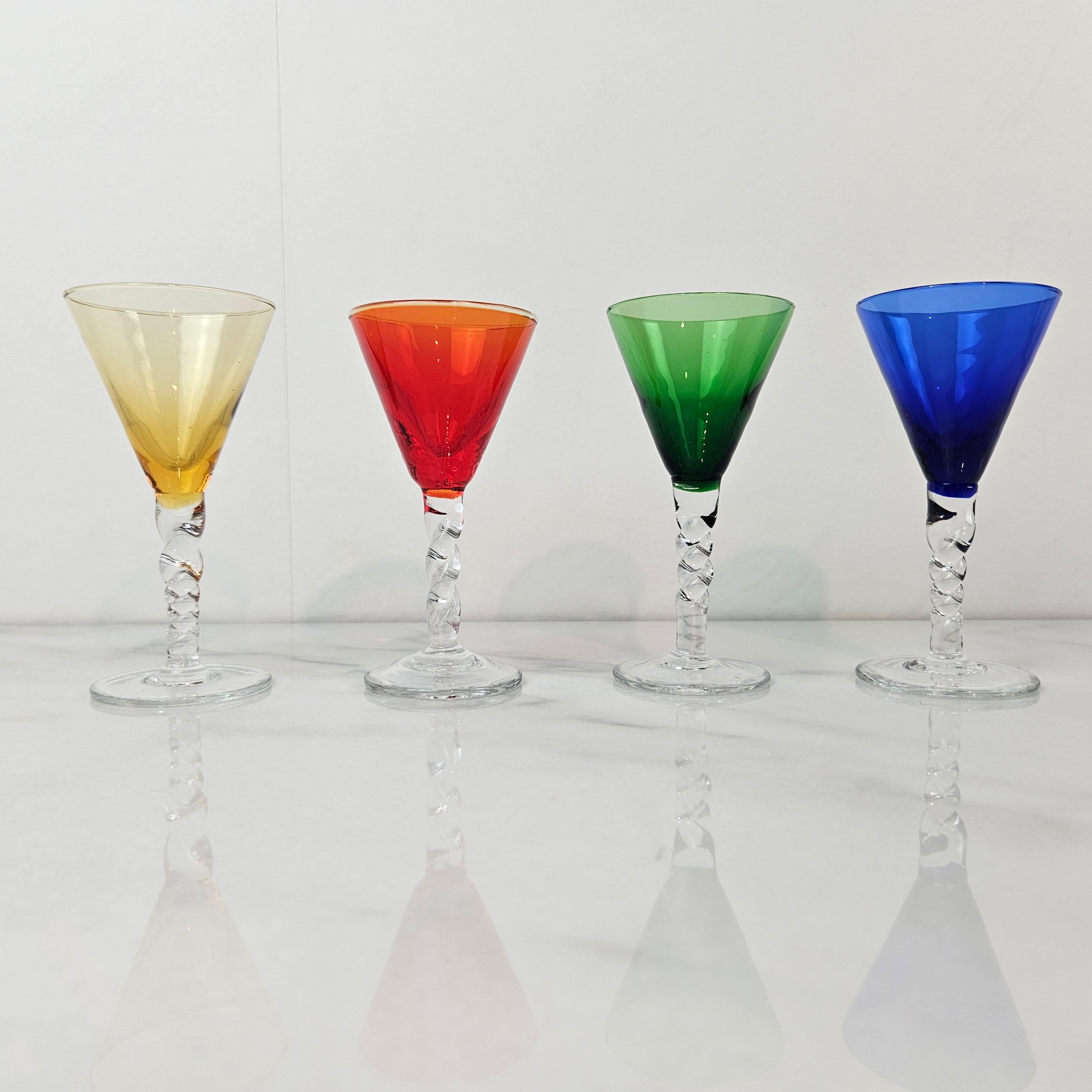 Un magnifique et rare ensemble de quatre verres à liqueur ou à cordial anciens, soufflés à la main et datant d'environ 1930. 
Chaque verre présente un bol finement soufflé à la main, gracieusement posé sur une tige torsadée transparente, déclinée