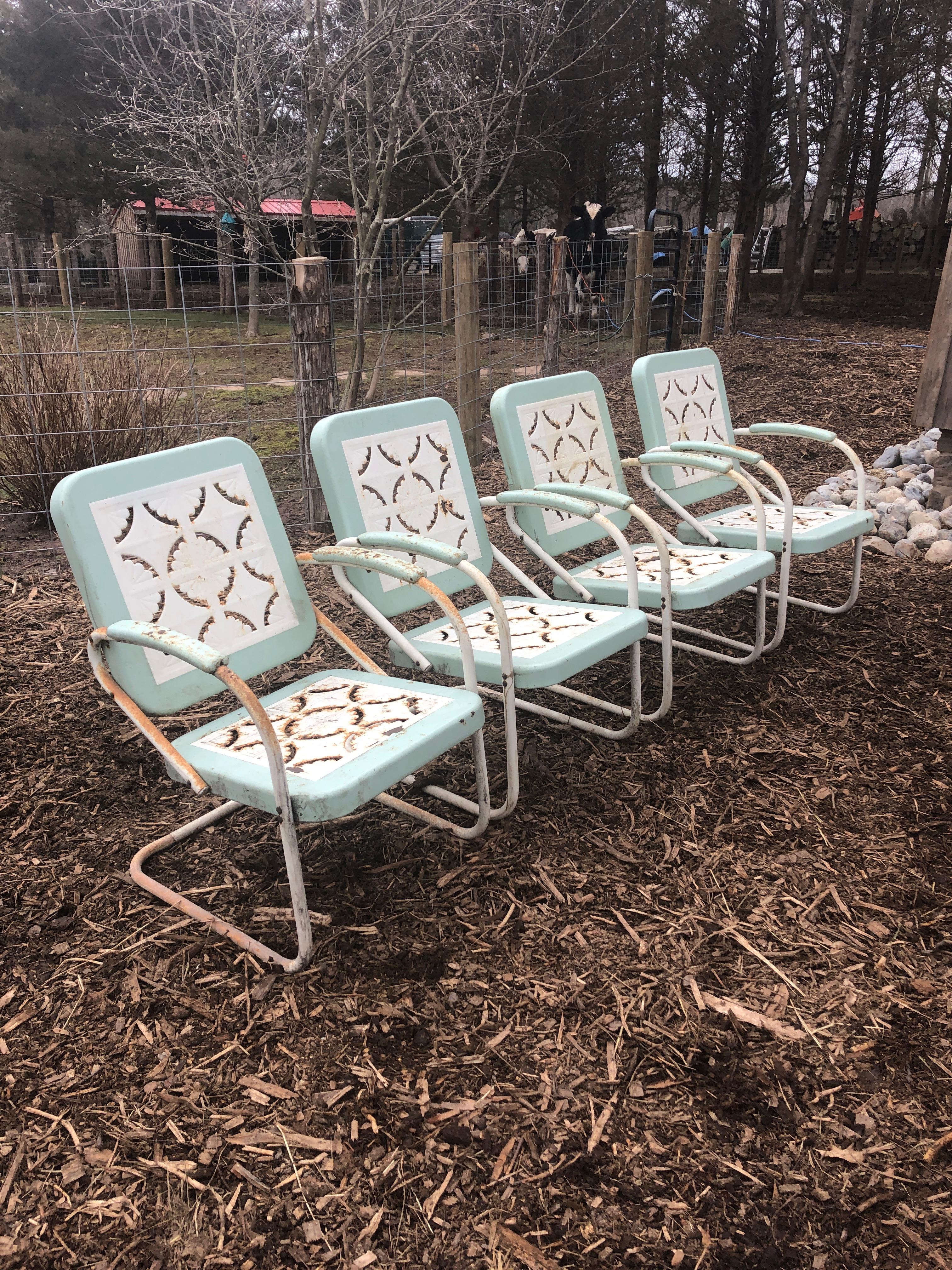 An inviting set of four classic country metal garden arm chairs having cut out charming patterns on the seats and backs. The color is white with light turquoise.
Measures: Arm height 24.5.