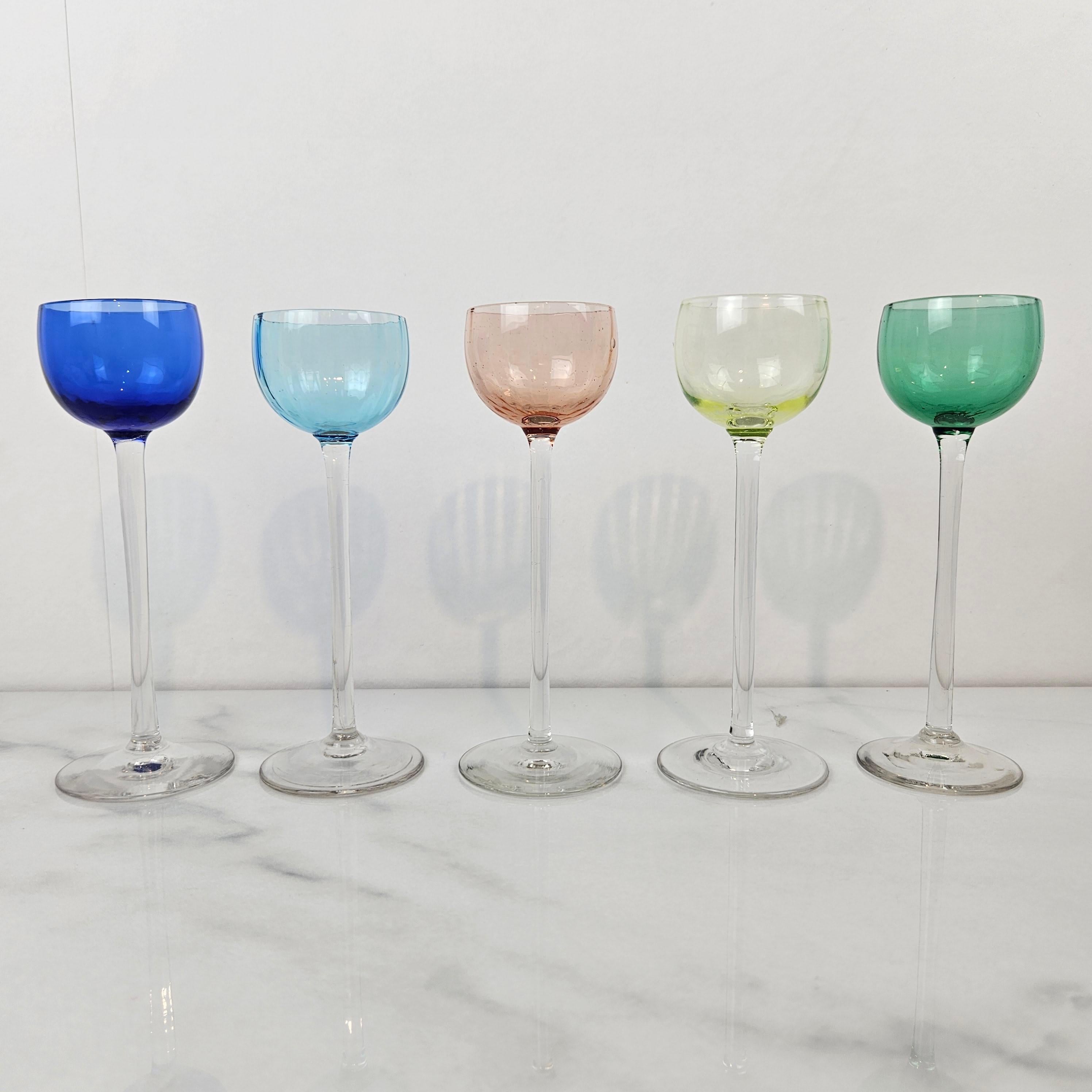 A beautiful and rare set of five antique liqueur or cordial glasses, hand-blown and dating to circa 1920. 
Each featuring a delicately handblown clear stem and subtly tinted bowl in shades of cobalt blue, sky blue, blush pink, pale yellow, and