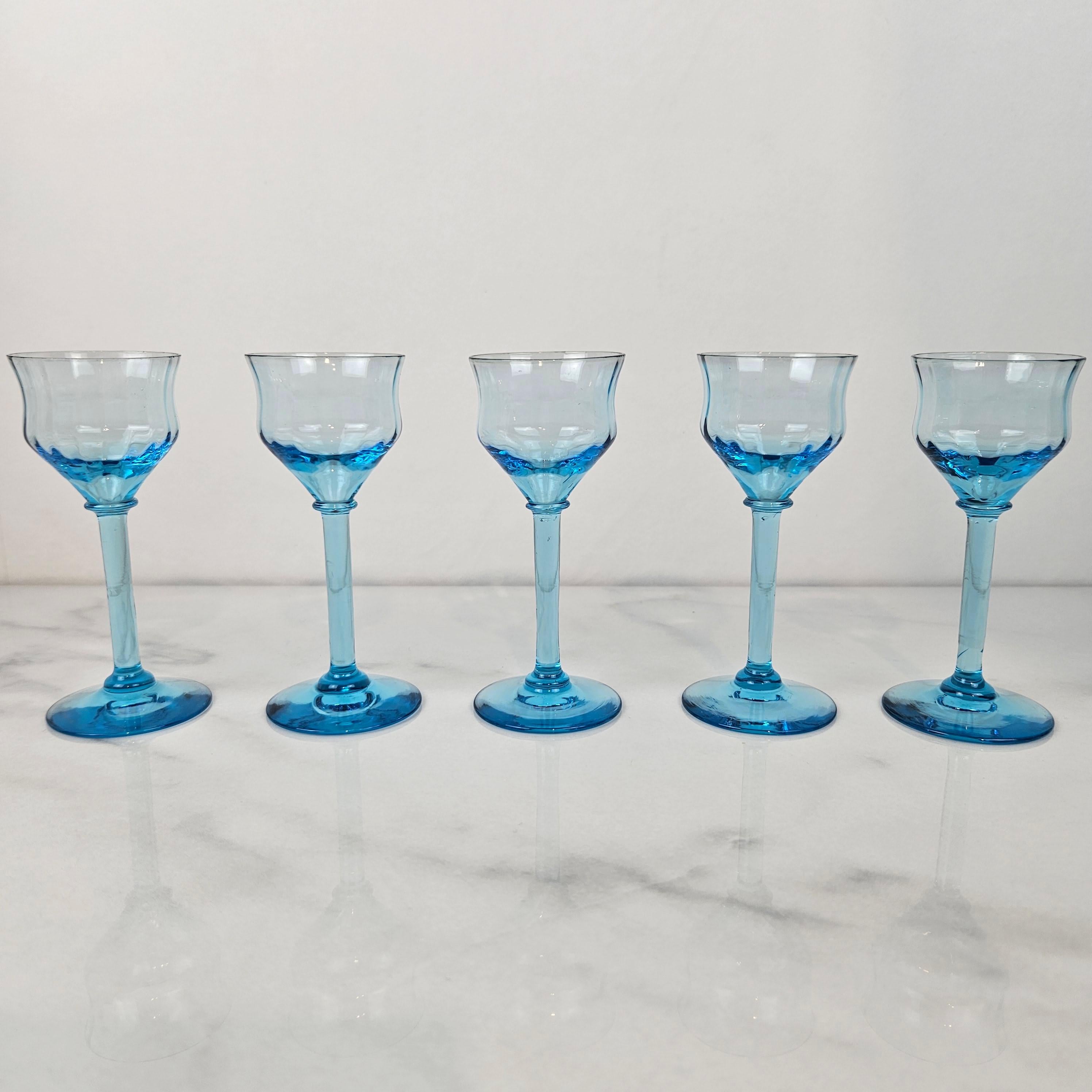 A sophisticated set of five Art Deco liqueur glasses from the 1920s, each one masterfully handblown in fully-colored blue glass. 
Because the color is integral to the glass itself — not painted or flashed — each piece shows a beautiful clarity and