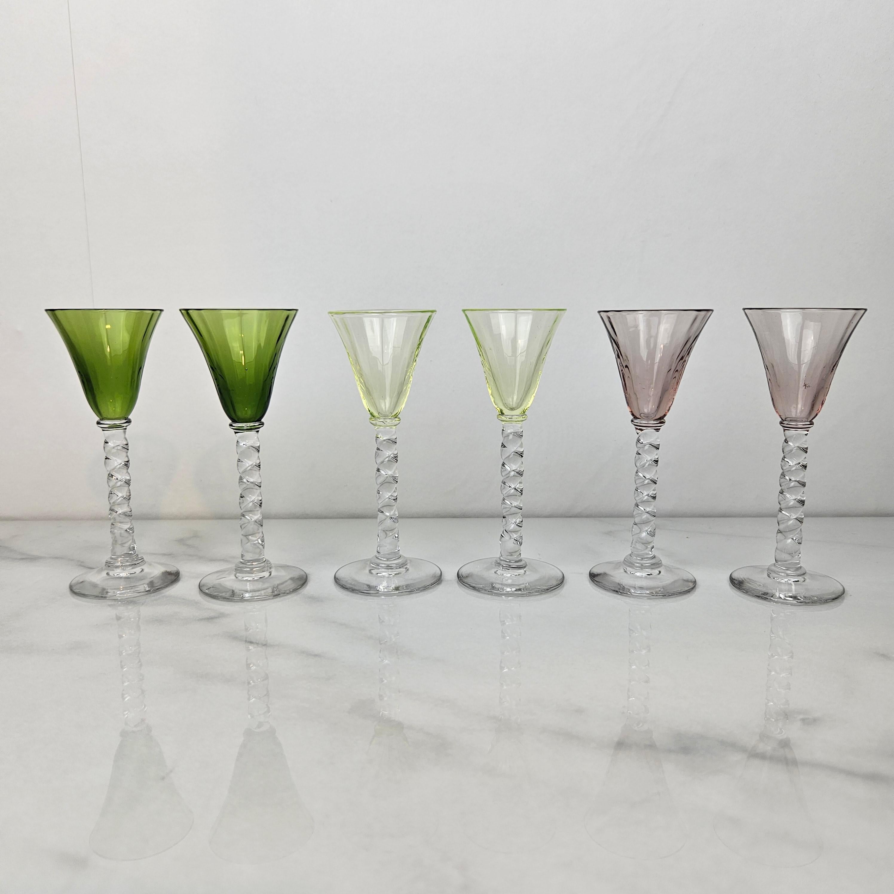 Un magnifique et rare ensemble de six verres à liqueur ou à cordial anciens, soufflés à la main et datant d'environ 1930. 
Chacune présente une tige claire et torsadée délicatement soufflée à la main et un bol subtilement nervuré dans des tons de