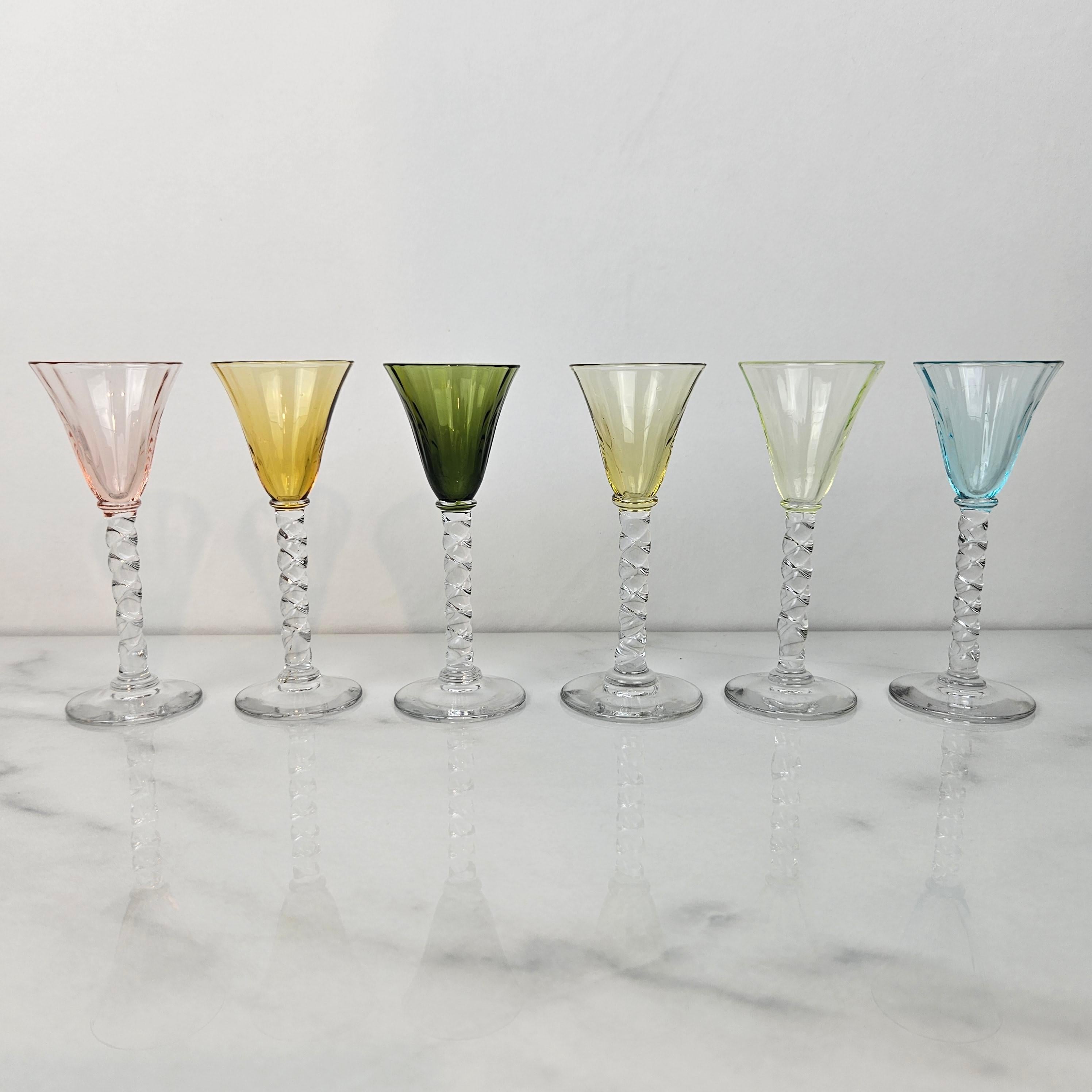 Un magnifique et rare ensemble de six verres à liqueur ou à cordial anciens, soufflés à la main et datant d'environ 1930. 
Chacune présente une tige claire et torsadée délicatement soufflée à la main et un bol subtilement nervuré dans des tons de