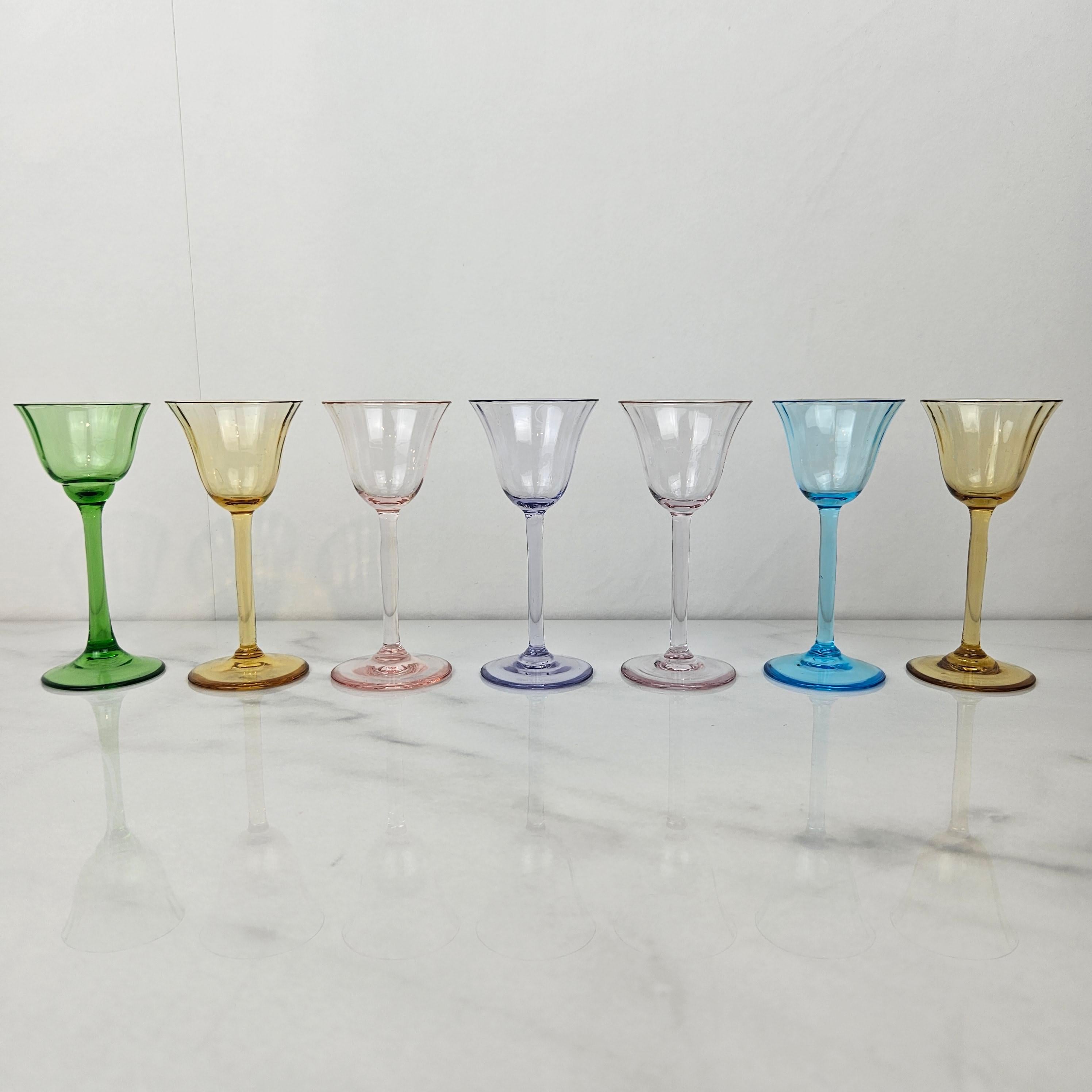 A sophisticated set of seven Art Deco liqueur glasses from the 1920s, each one masterfully handblown in fully-colored glass. 
Because the color is integral to the glass itself — not painted or flashed — each piece shows a beautiful clarity and