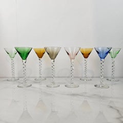 Charmant ensemble de 8 verres à liqueur colorés à long pied torsadé, ca. 1930